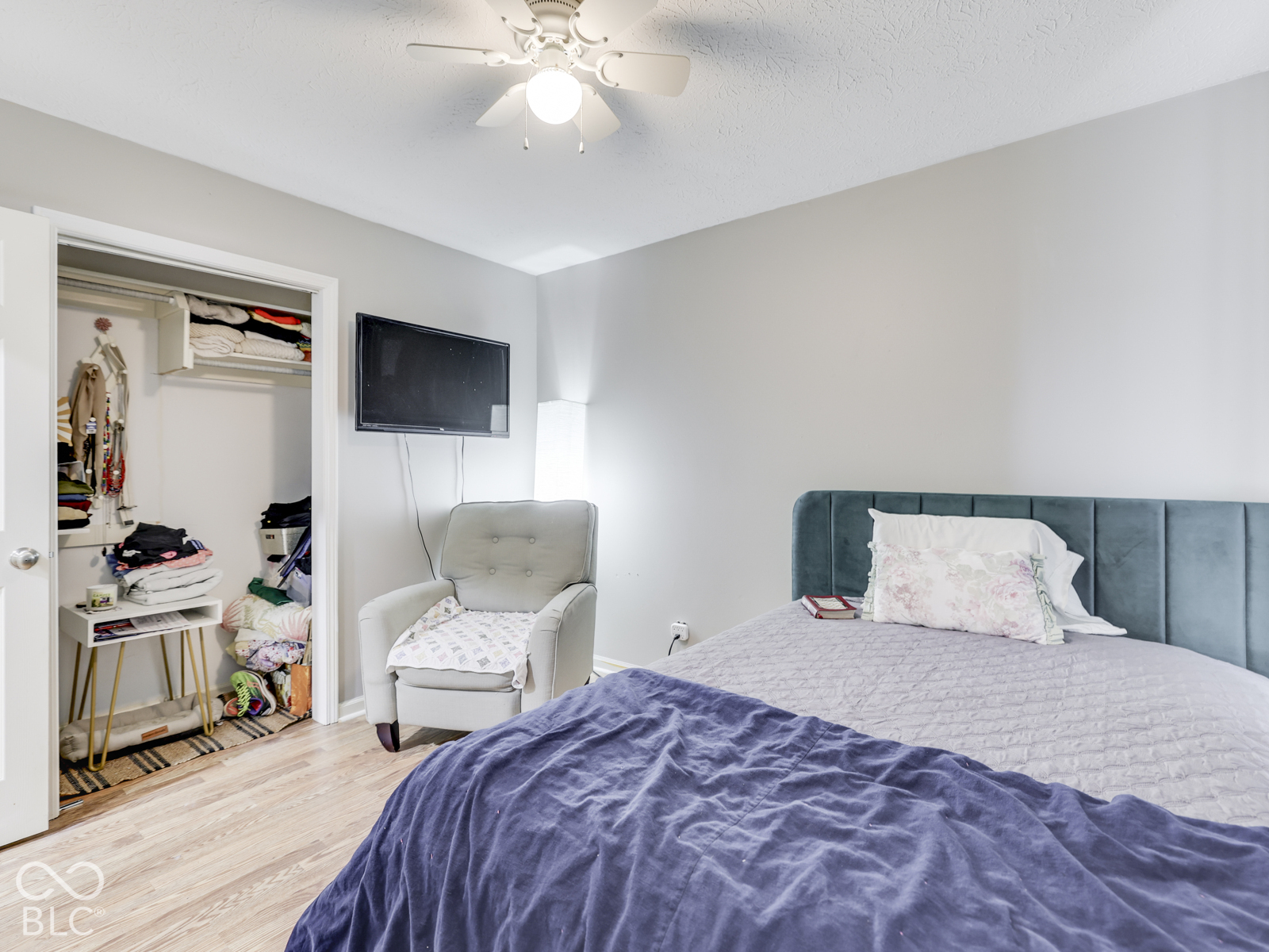 Neutral wall palette with wood-finish flooring, ceiling fan with integrated lighting, and walk-in closet featuring built-in shelving