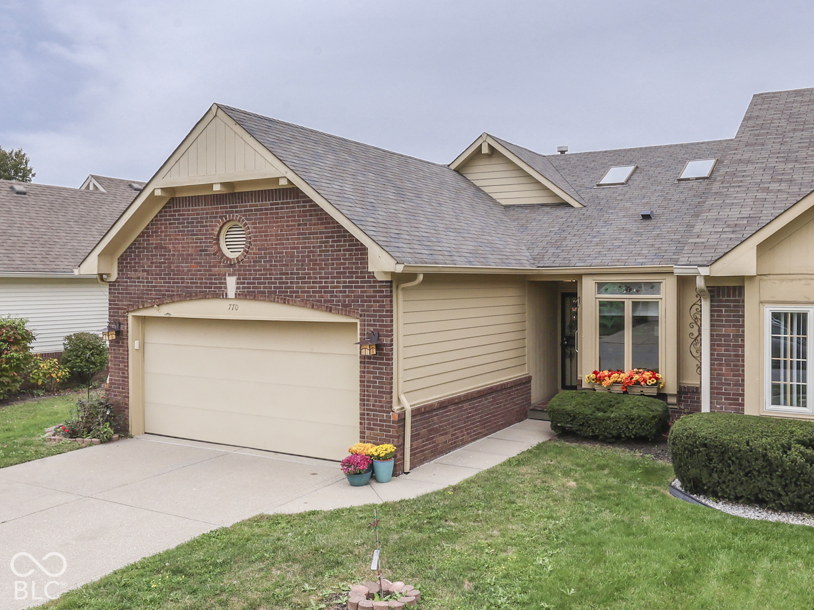 Exterior facade featuring a combination of brick and horizontal siding, an attached two-car garage, roof-integrated skylights, a recessed entry, and double-hung windows with grilles