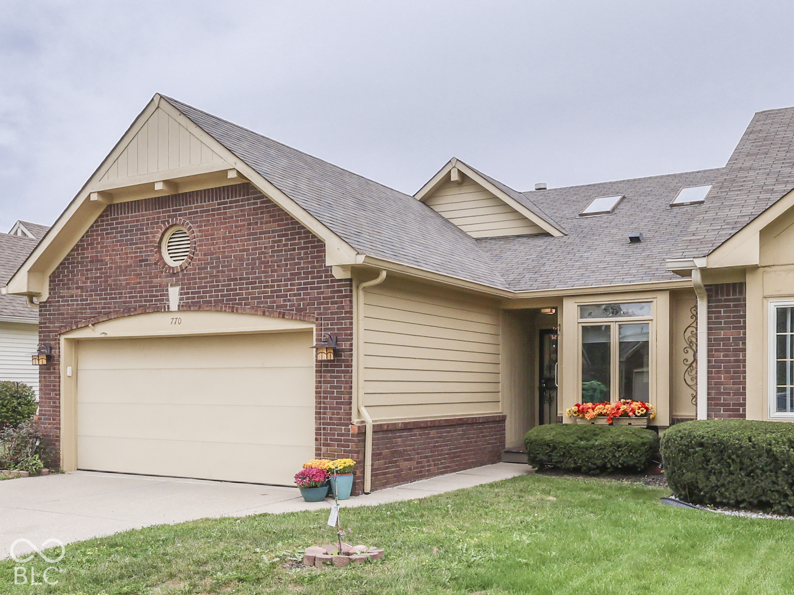 Brick and horizontal siding exterior featuring a gabled roofline, arched garage door entry, and roof-integrated skylights