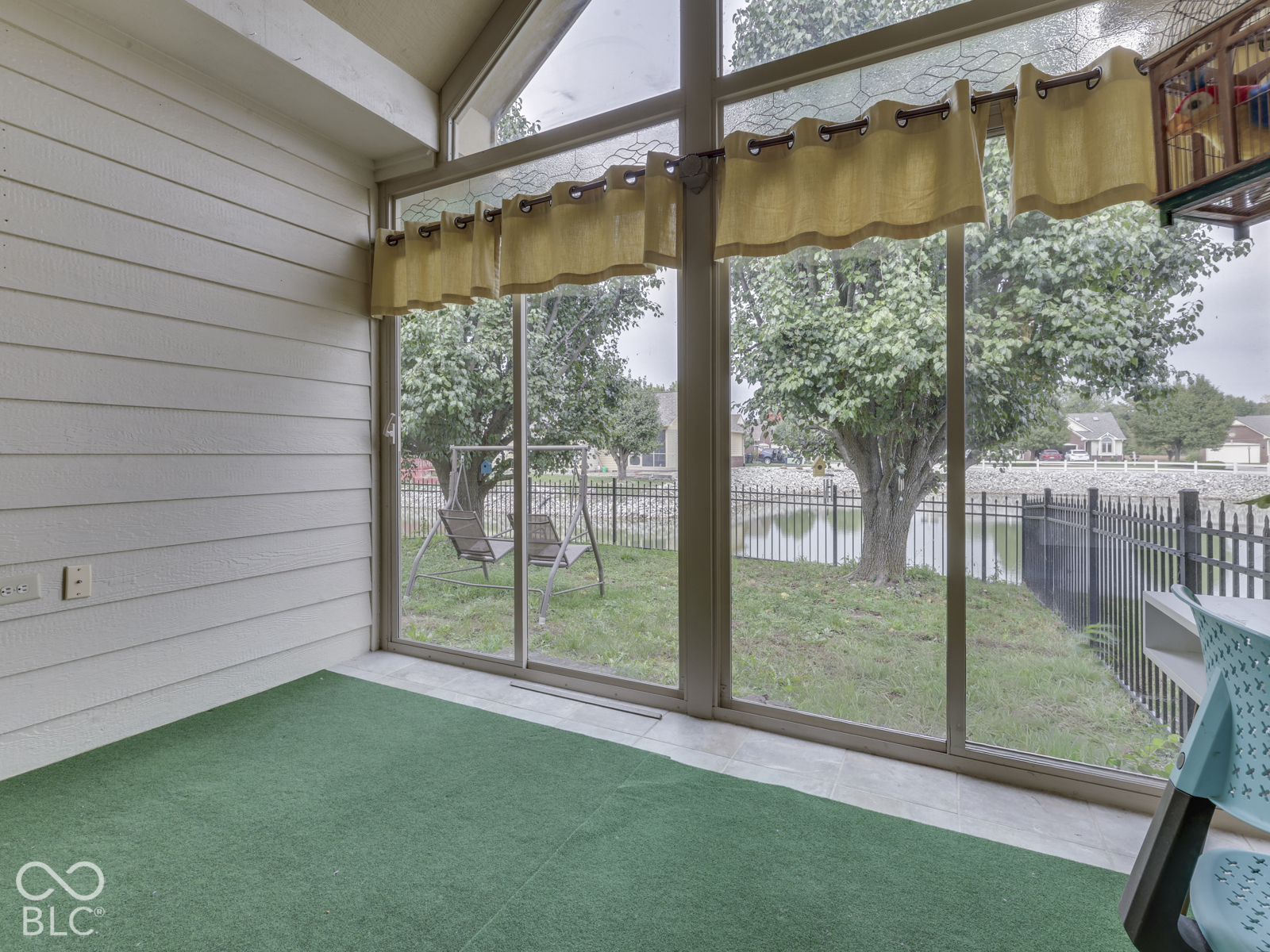 Sunroom featuring horizontal paneled walls, vaulted ceiling, and expansive floor-to-ceiling glass sliding doors with aluminum framing