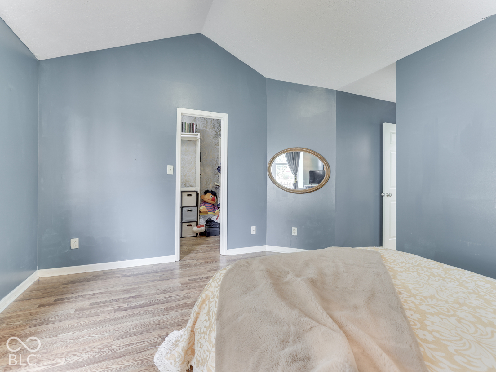 Vaulted ceilings, wood-finish flooring, and a wall-mounted oval mirror
