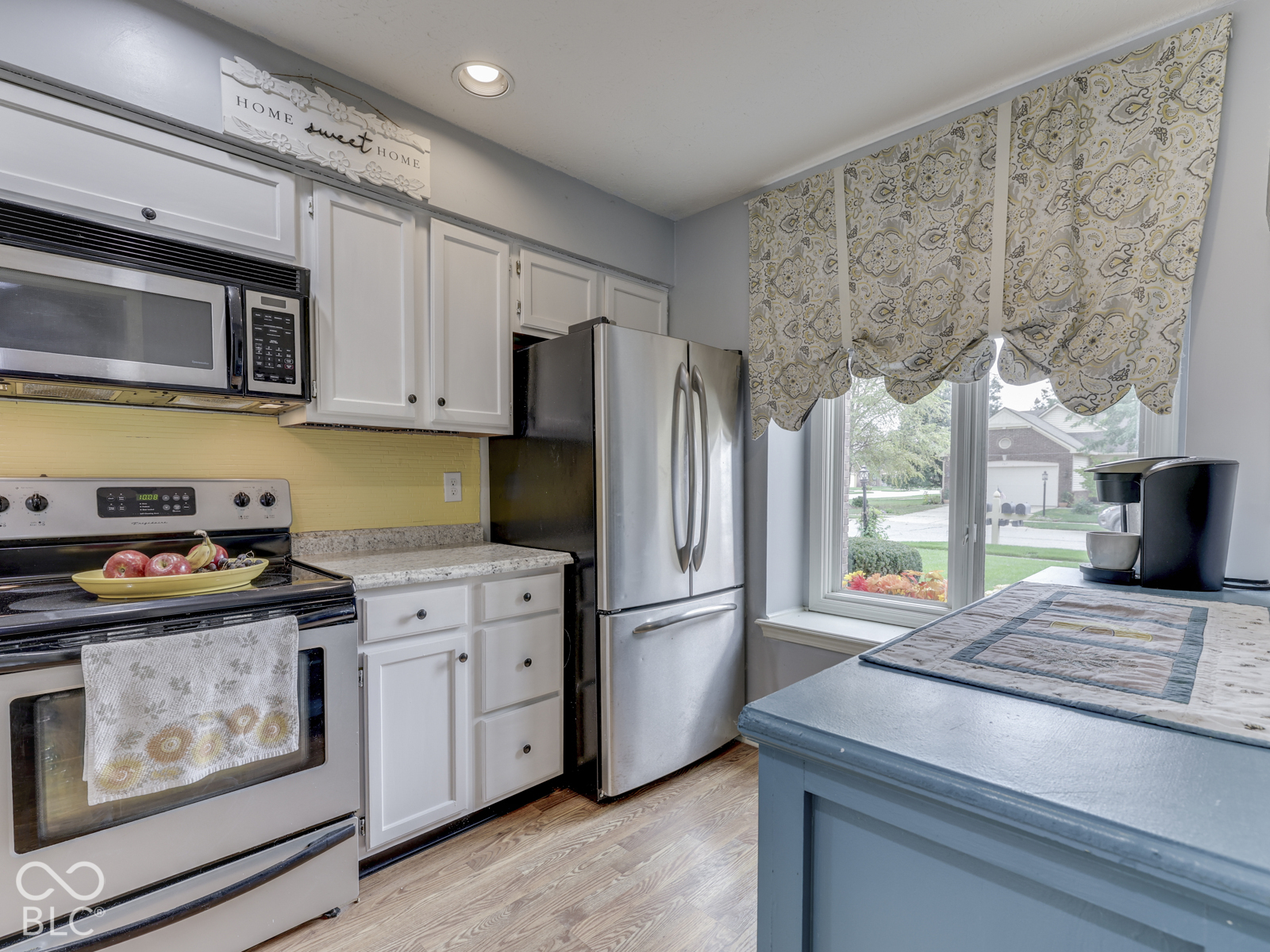 Kitchen featuring white cabinetry, stone-finish countertops, stainless steel appliances, wood-finish flooring, and a large window