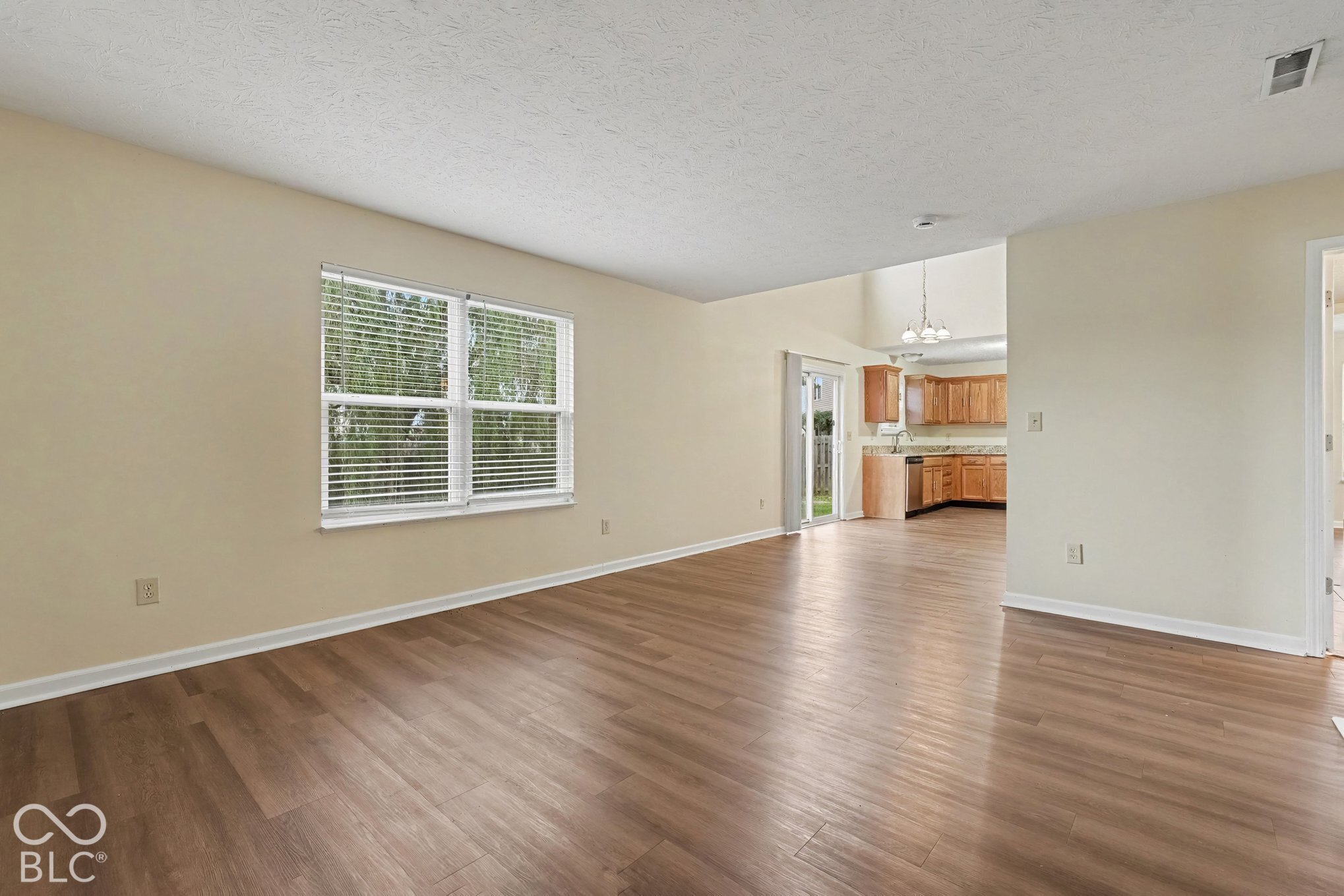 Living area featuring wood-finish flooring, neutral wall paint, and multi-pane window with blinds