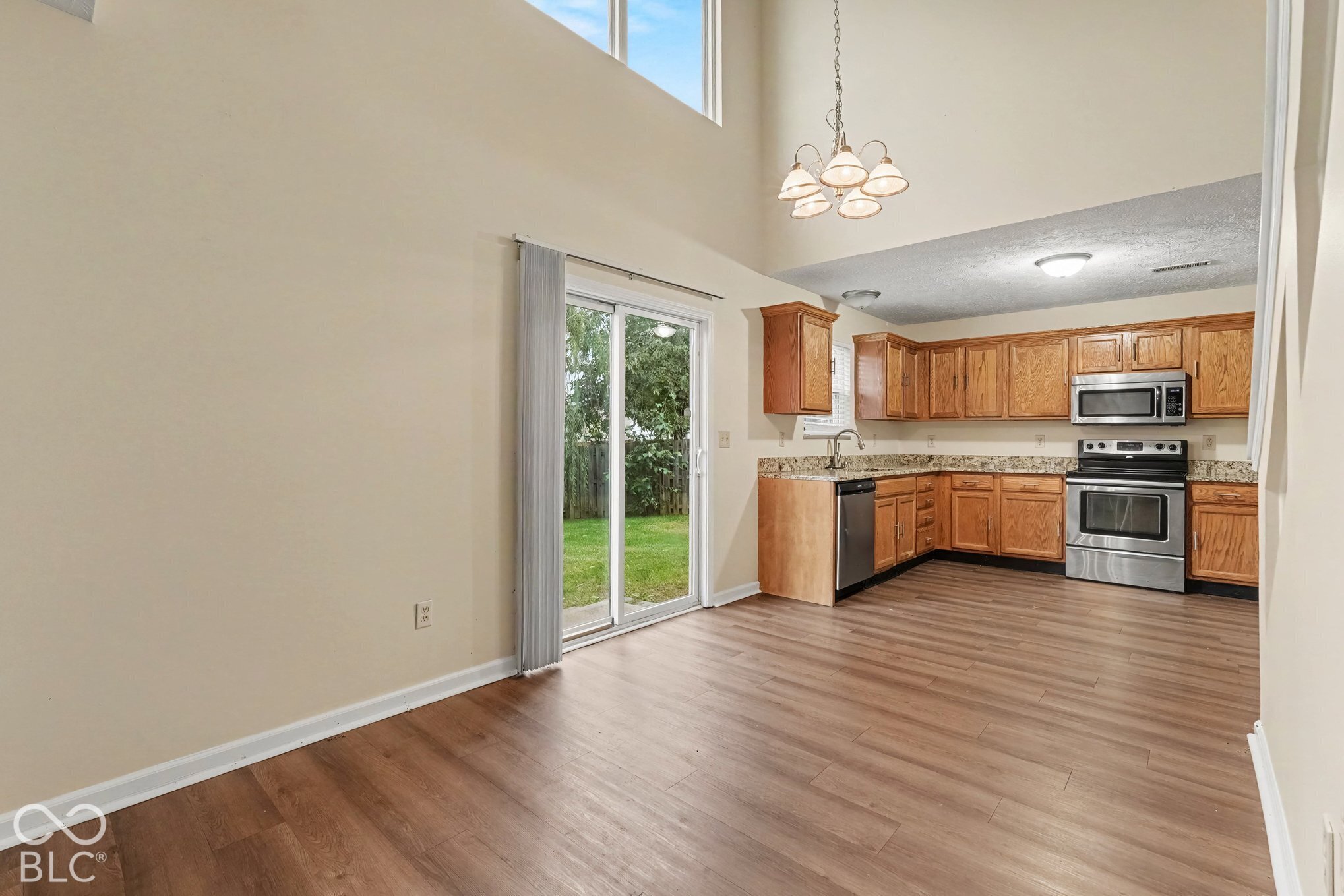 Vaulted ceilings, wood-finish flooring, sliding glass door, natural stone-surface countertops, and stainless steel kitchen appliances