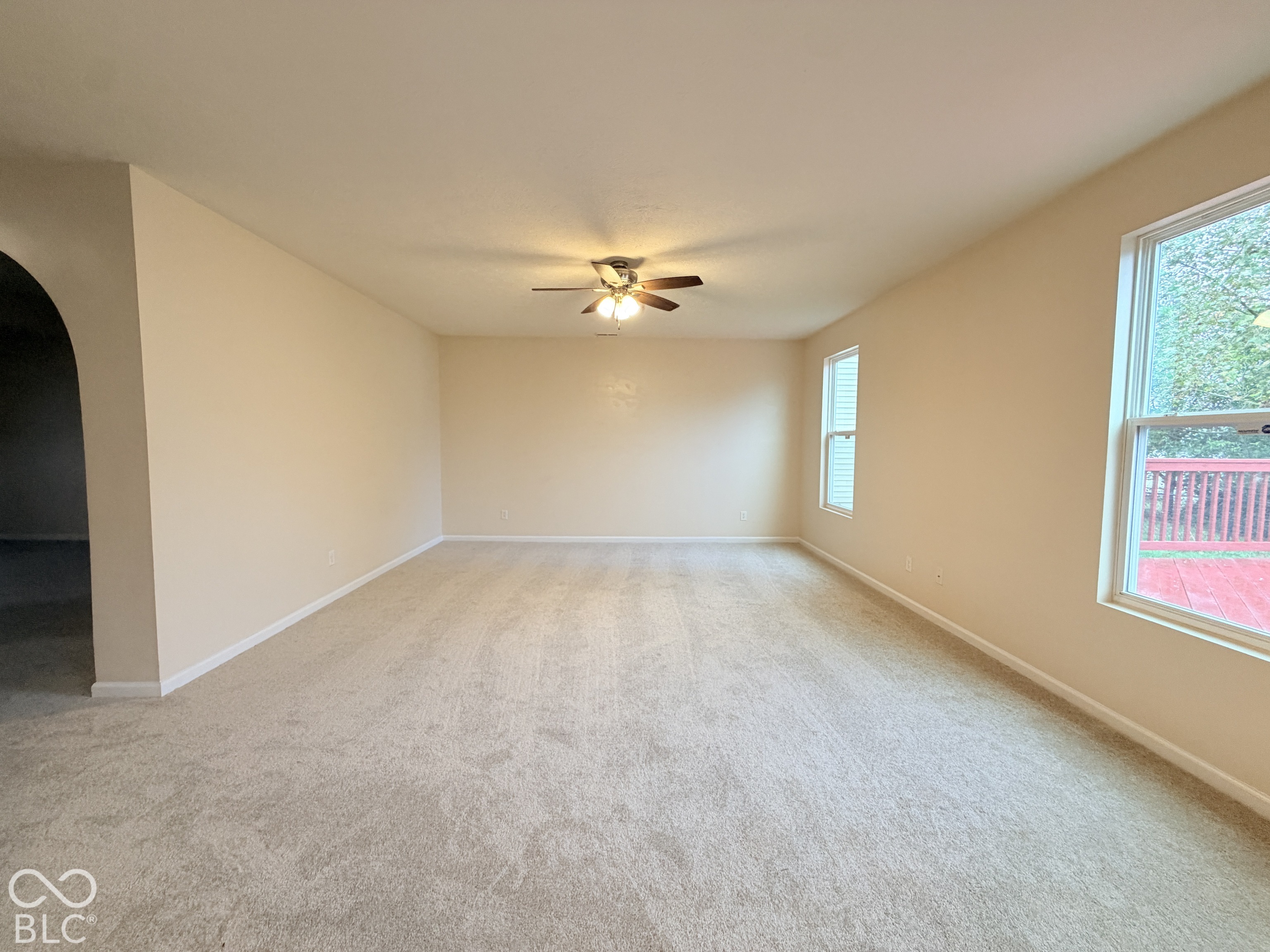 Neutral wall-to-wall carpeting, ceiling fan with light fixture, and large dual-pane windows Neutral wall-to-wall carpeting, ceiling fan with light fixture, and large dual-pane windows