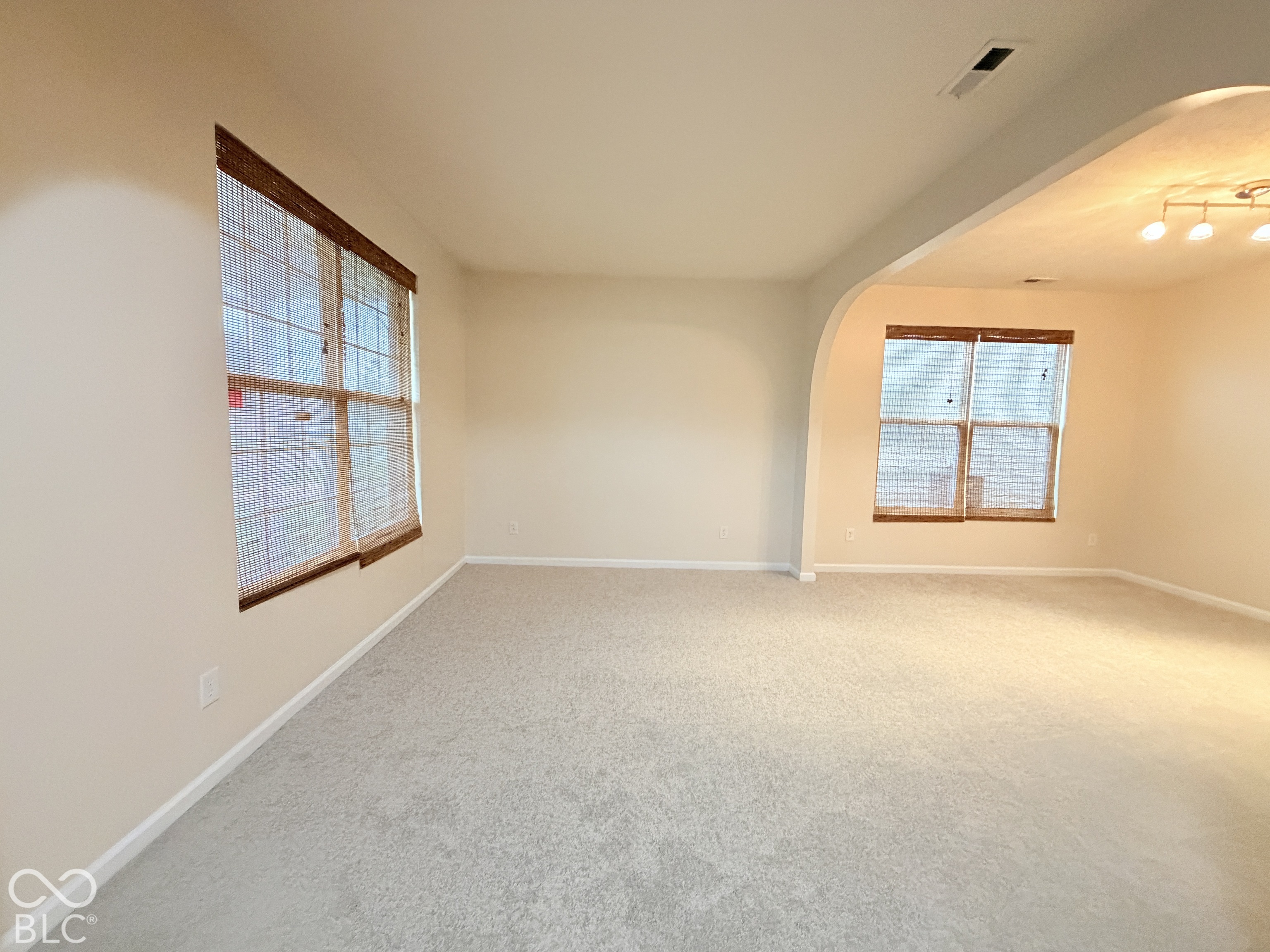 Neutral carpeted flooring, arched architectural opening, and multi-pane windows with integrated wooden-finish trim Neutral carpeted flooring, arched architectural opening, and multi-pane windows with integrated wooden-finish trim