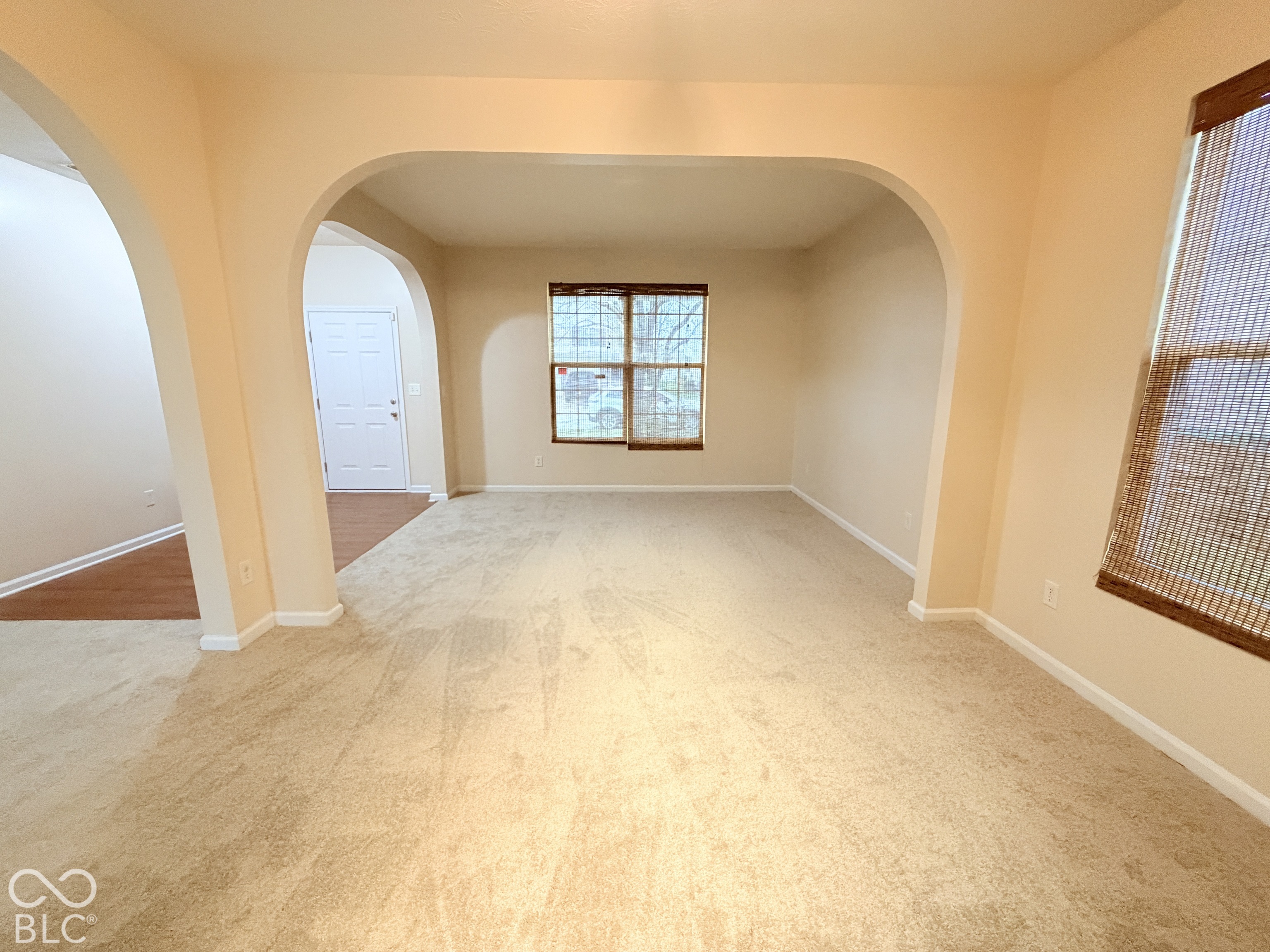 Interior space featuring arched architectural detailing, neutral wall tones, multi-pane windows, and wall-to-wall carpeting Interior space featuring arched architectural detailing, neutral wall tones, multi-pane windows, and wall-to-wall carpeting