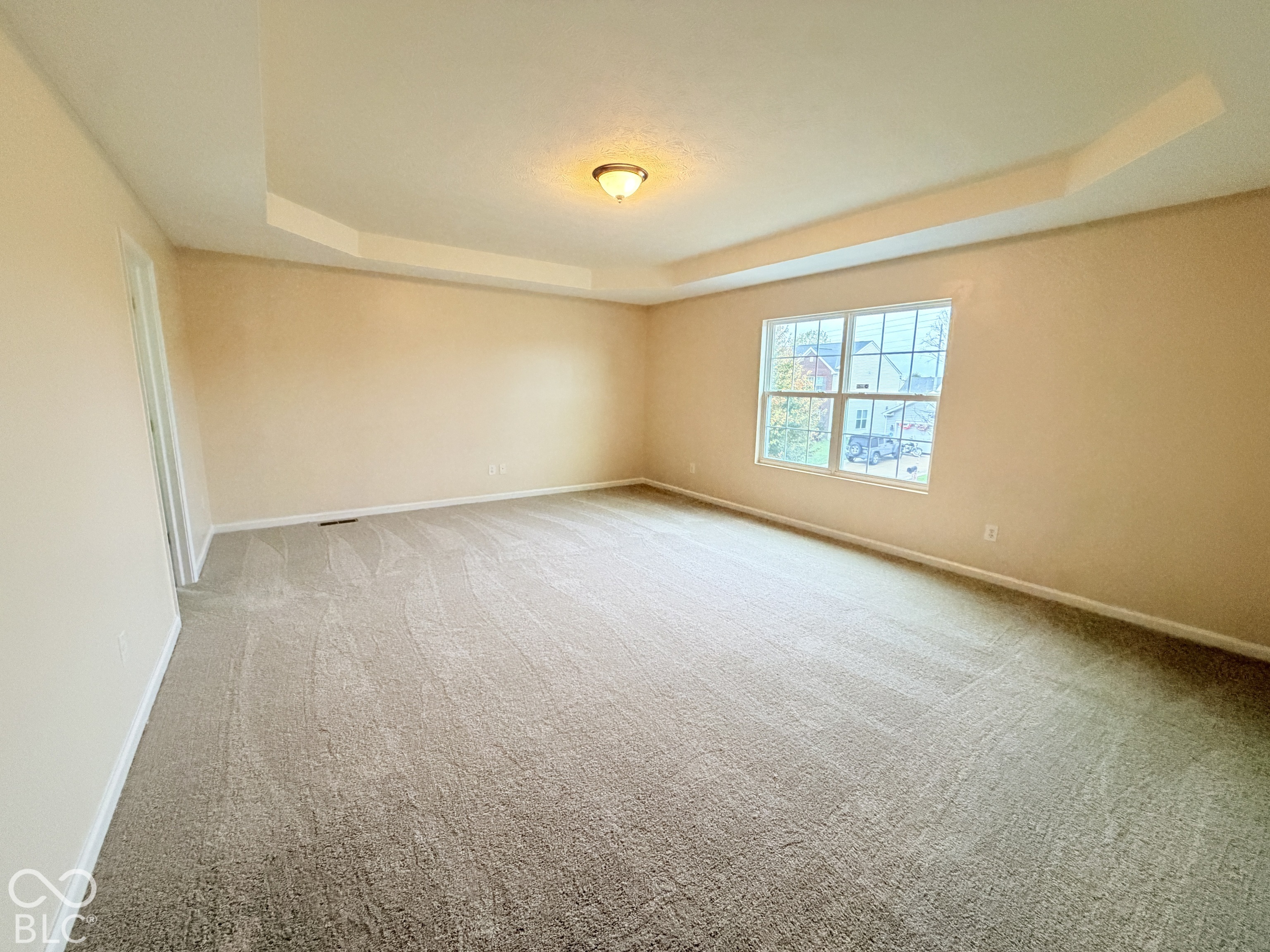 Tray ceiling, neutral wall tones, carpeted flooring, and a multi-pane window