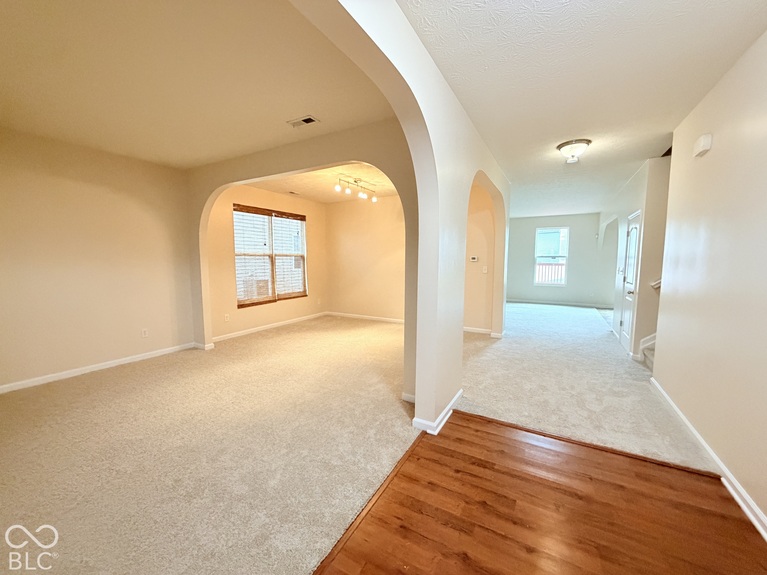 Interior featuring arched architectural detailing, neutral carpeting, wood-finish flooring, and multi-light fixtures Interior featuring arched architectural detailing, neutral carpeting, wood-finish flooring, and multi-light fixtures