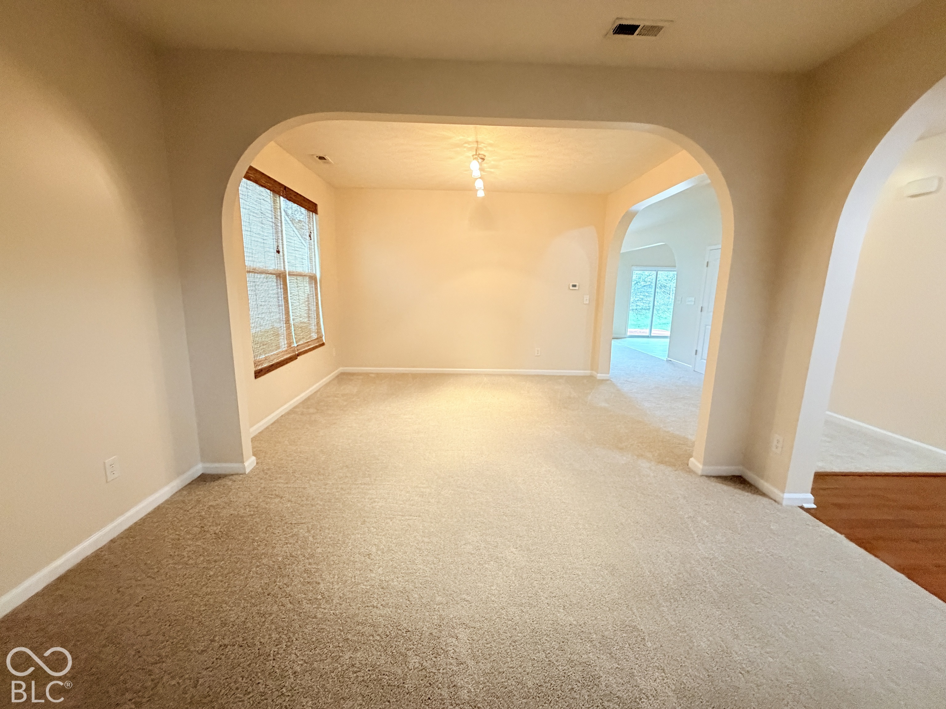 Architectural archways, multi-pane windows with trim, neutral wall coloring, and wall-mounted overhead lighting Architectural archways, multi-pane windows with trim, neutral wall coloring, and wall-mounted overhead lighting