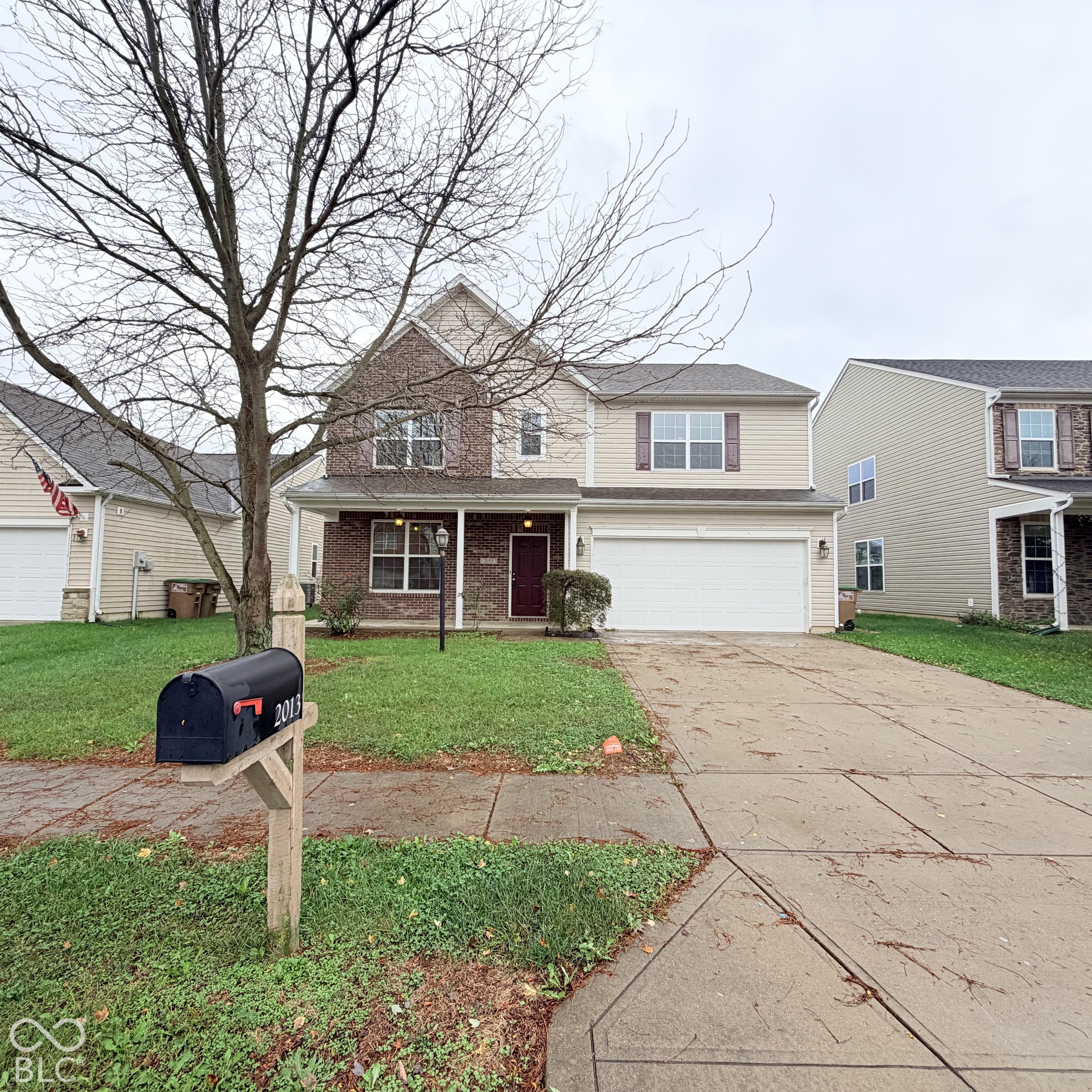 Two-story residence with a brick and vinyl siding exterior, featuring a covered front porch, an attached two-car garage, and a concrete driveway Two-story residence with a brick and vinyl siding exterior, featuring a covered front porch, an attached two-car garage, and a concrete driveway