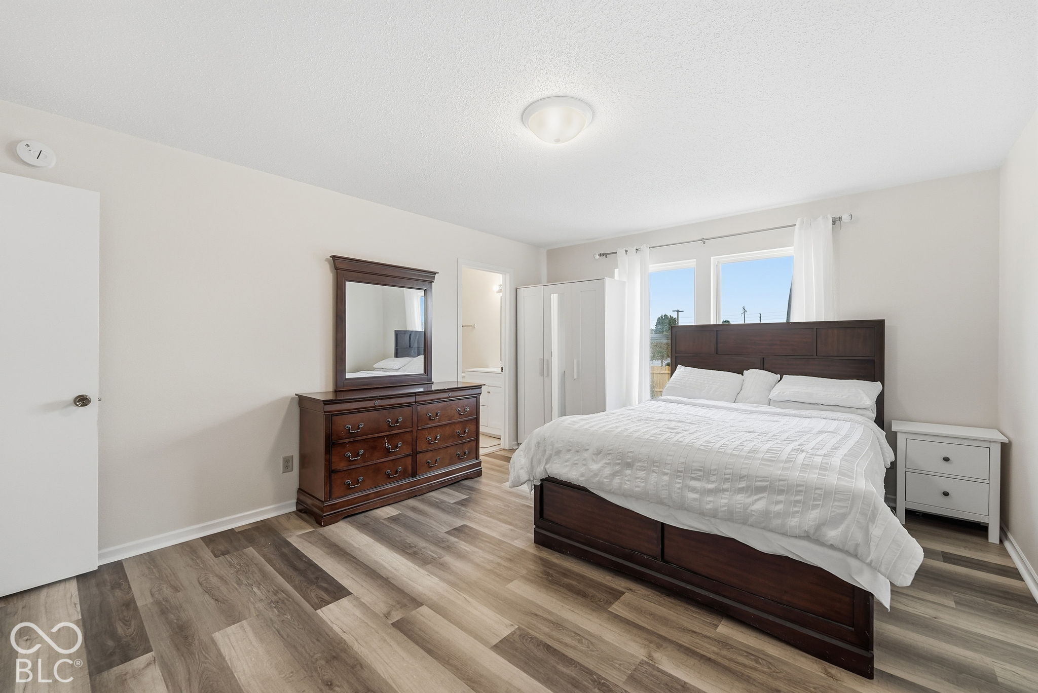 Neutral-toned walls, wood-finish flooring, dual windows, and a flush-mount ceiling fixture