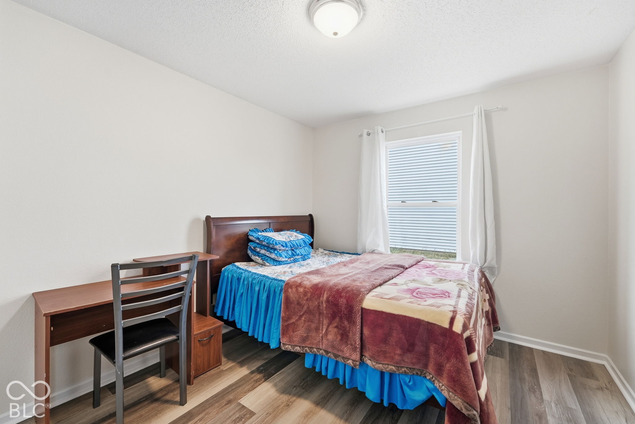 Neutral interior featuring wood-finish flooring, a double-hung window, and a flush-mount ceiling light fixture