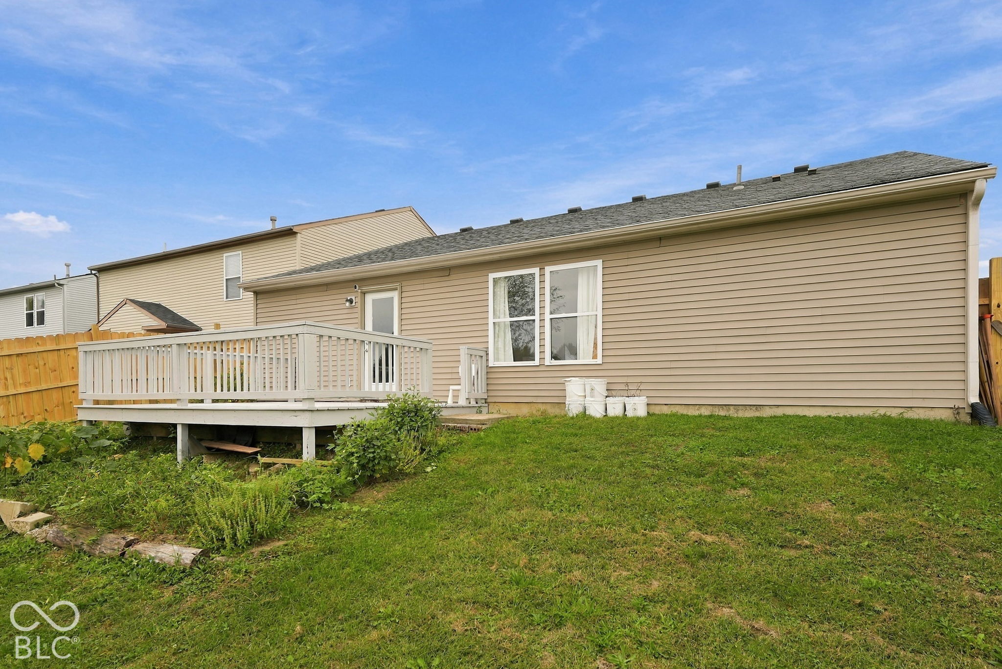 Exterior featuring vinyl siding, a rear wood deck, and a fenced yard