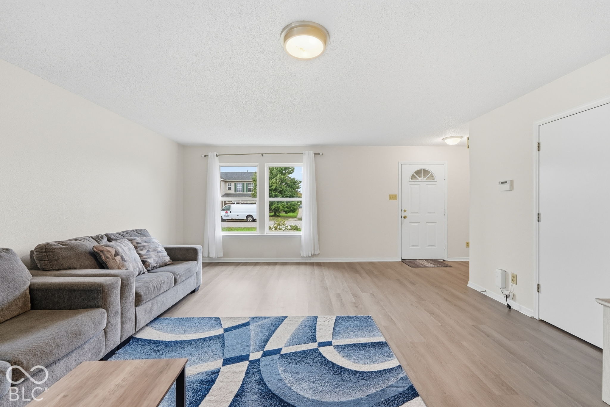 Neutral interior featuring wood-finish flooring, crisp white walls, dual-pane windows, and flush-mount ceiling lighting Neutral interior featuring wood-finish flooring, crisp white walls, dual-pane windows, and flush-mount ceiling lighting