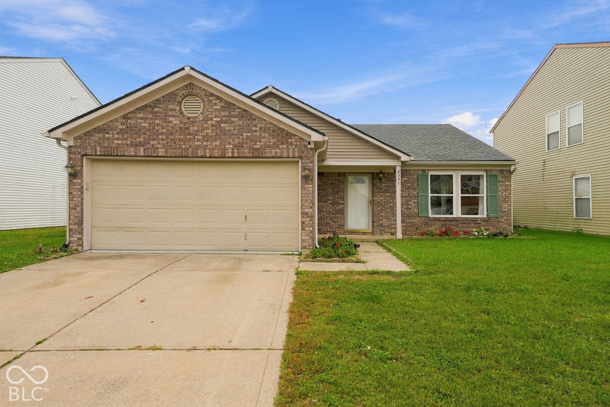 Brick and vinyl siding exterior featuring a front-facing attached garage, concrete driveway, and shuttered windows Brick and vinyl siding exterior featuring a front-facing attached garage, concrete driveway, and shuttered windows