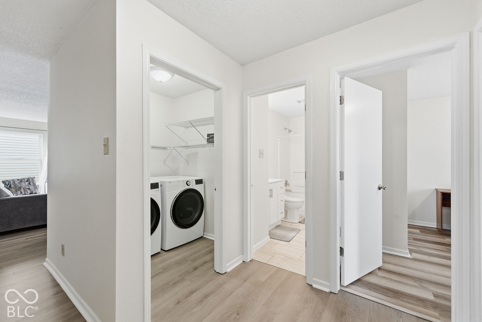 Neutral-toned wood-finish flooring, dedicated laundry nook with built-in shelving, and tile flooring in the bathroom