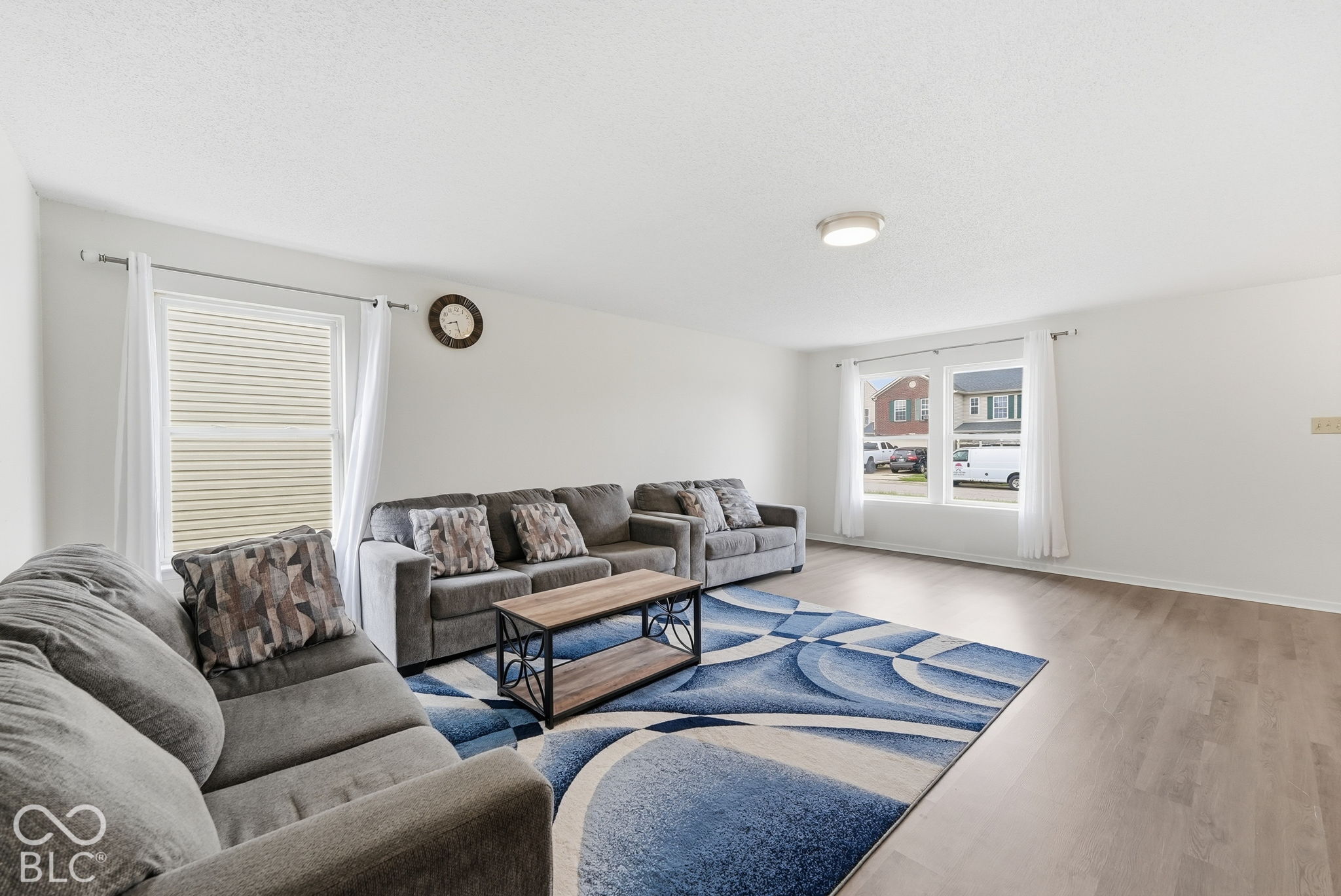 Neutral-toned interior space featuring wood-finish flooring, crisp white walls, and multiple dual-pane windows