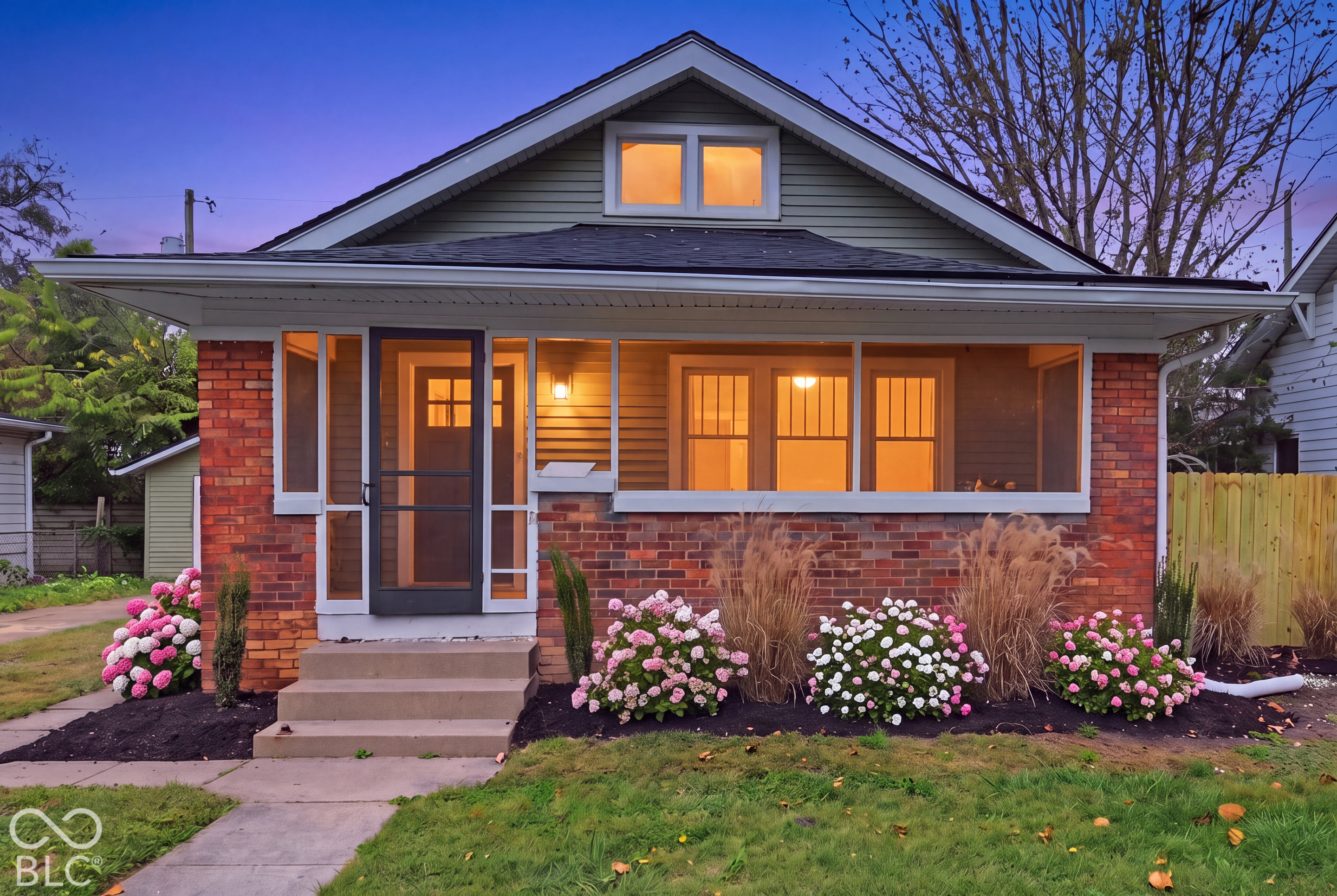 Bungalow exterior featuring a classic red brick facade, horizontal lap siding, a covered front porch with a screen enclosure, and a prominent gable roofline