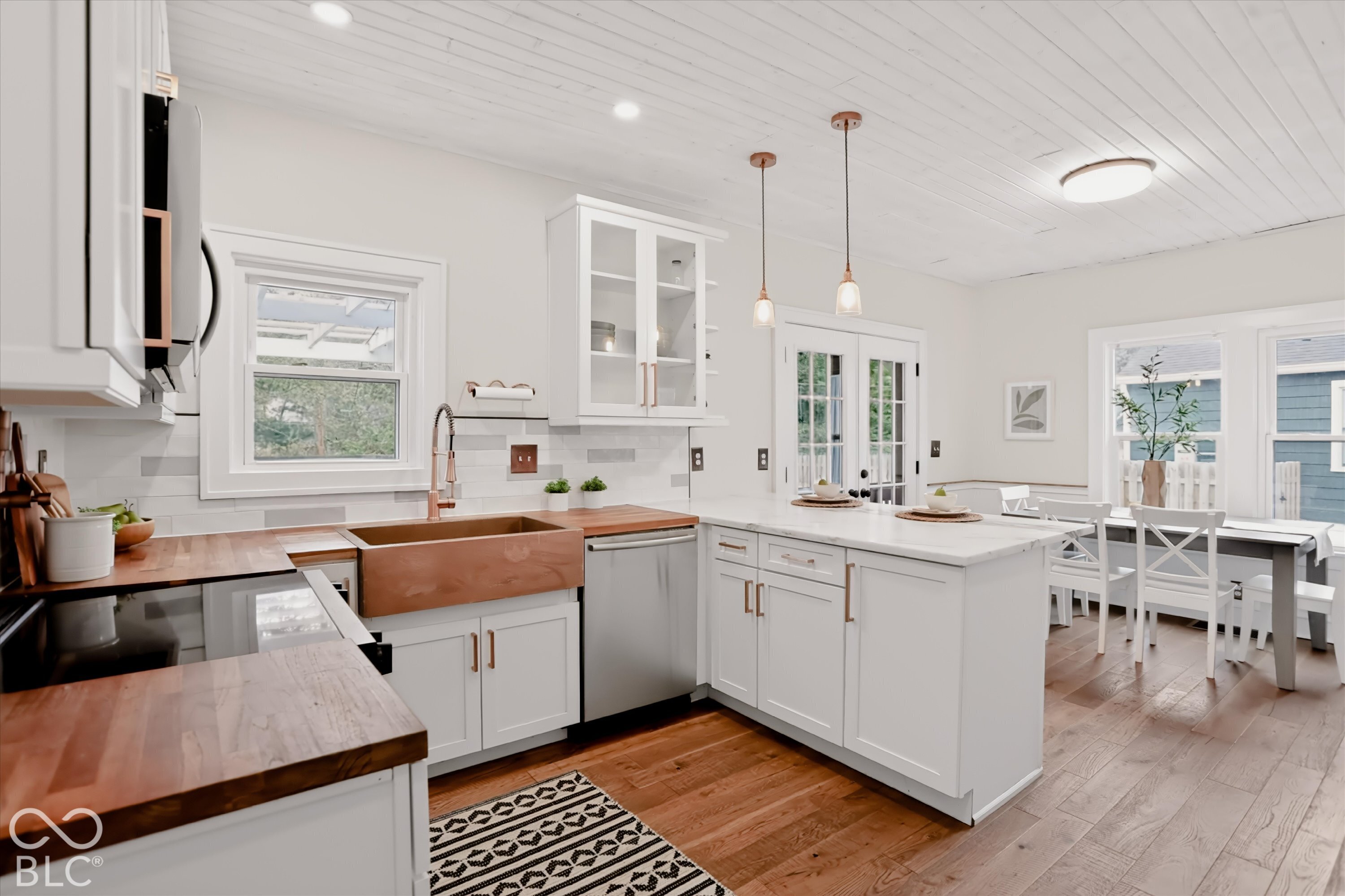 Kitchen featuring white shaker-style cabinetry, wood-finish countertops, apron-front copper sink, wood-finish flooring, and shiplap ceiling
