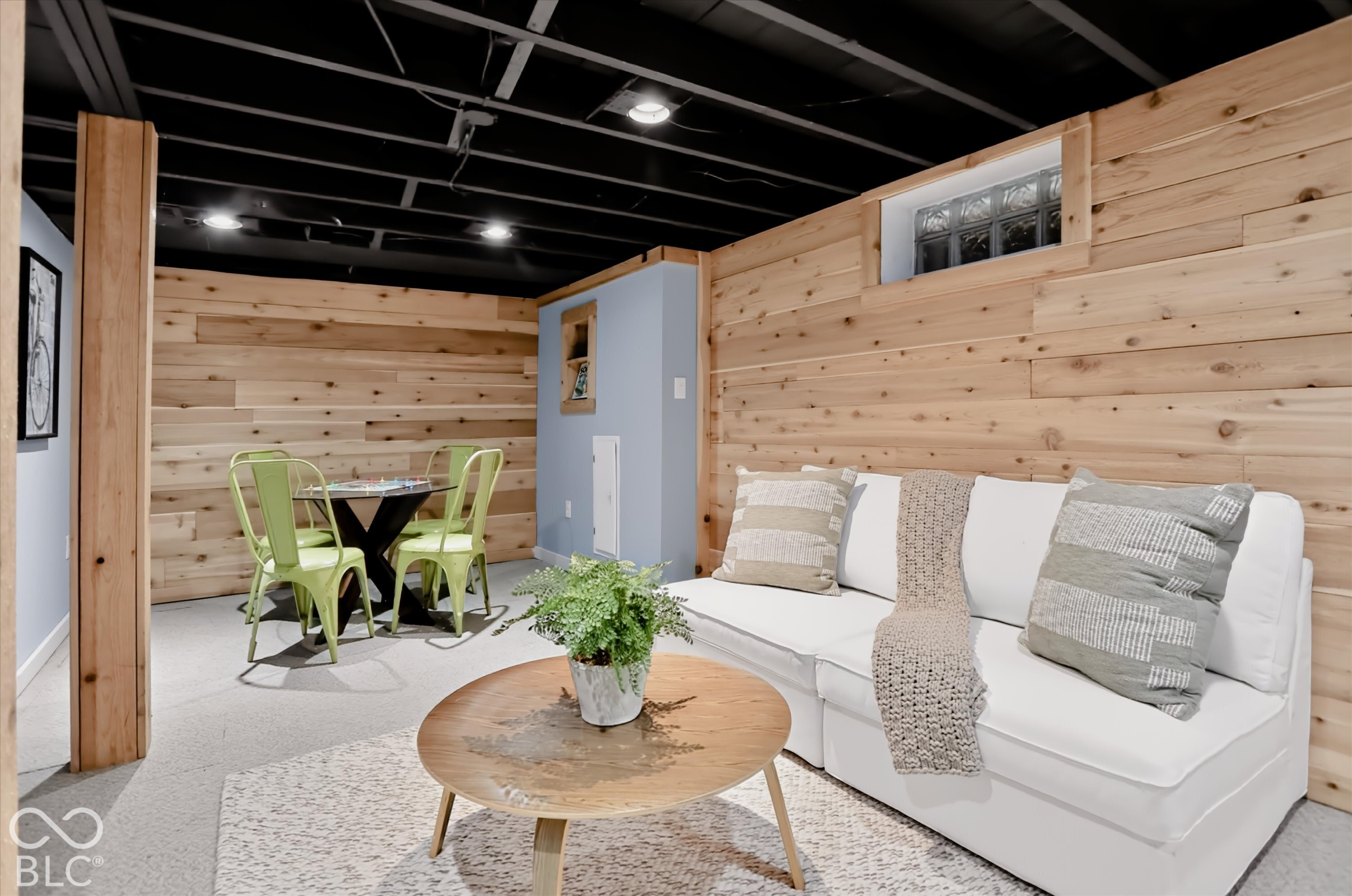 Finished interior space featuring horizontal wood-plank wall paneling, an exposed painted ceiling with recessed lighting, and a glass-block window