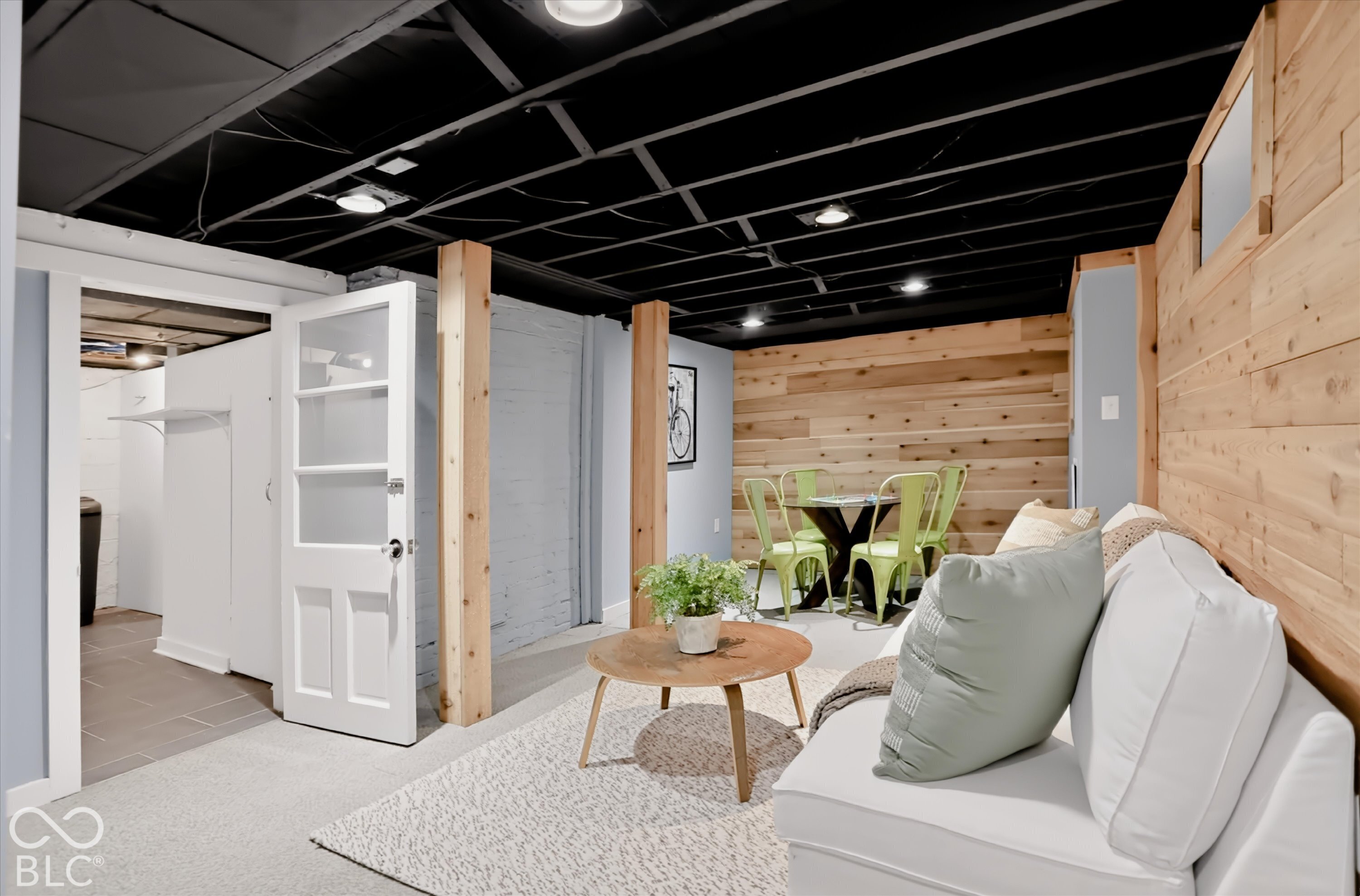 Exposed black-painted ceiling, natural wood-paneled walls, structural wood support posts, and inset ceiling lighting