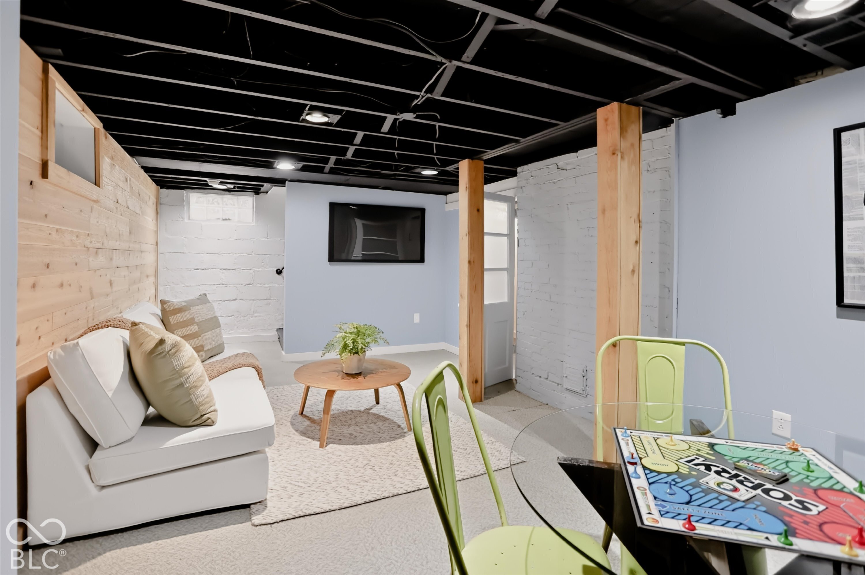 Finished space featuring exposed ceiling joists, wood-plank accent wall, painted masonry walls, and integrated recessed lighting