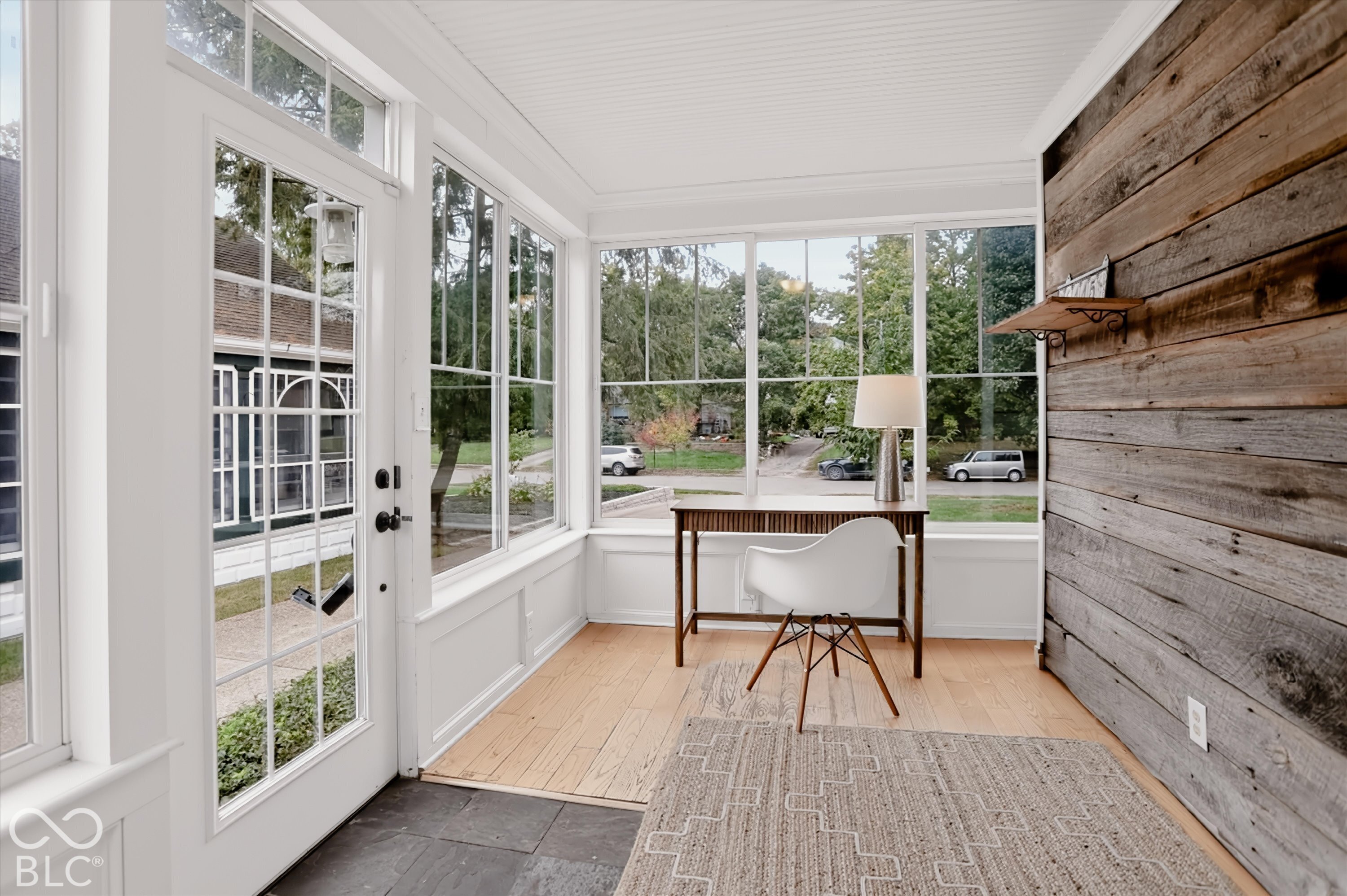 Sunroom featuring a plank-style wood accent wall, extensive window coverage, light-toned wood flooring, beadboard ceiling, and slate-finish flooring