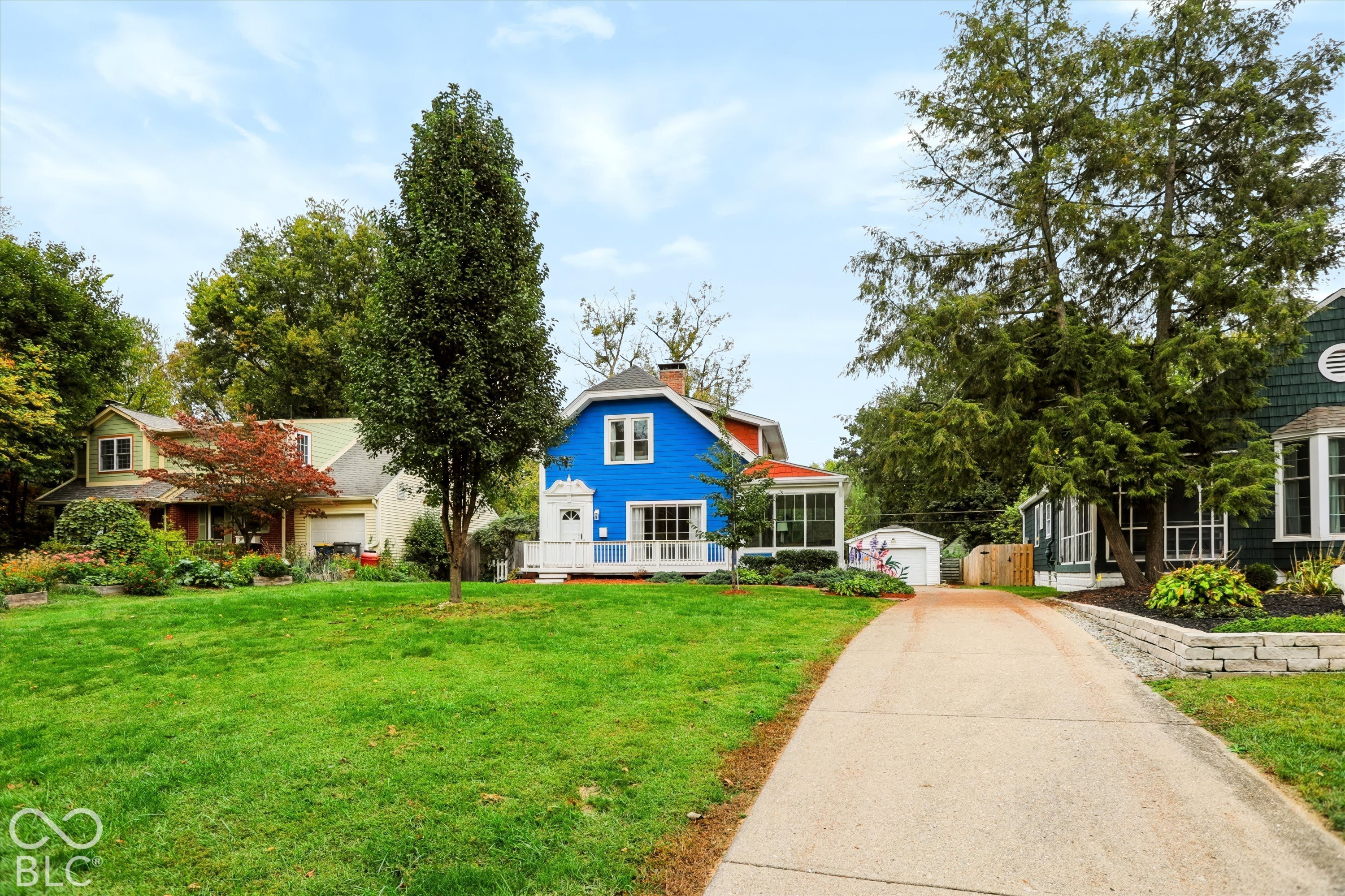 Exterior featuring blue siding, a front porch, a concrete driveway, and a detached garage