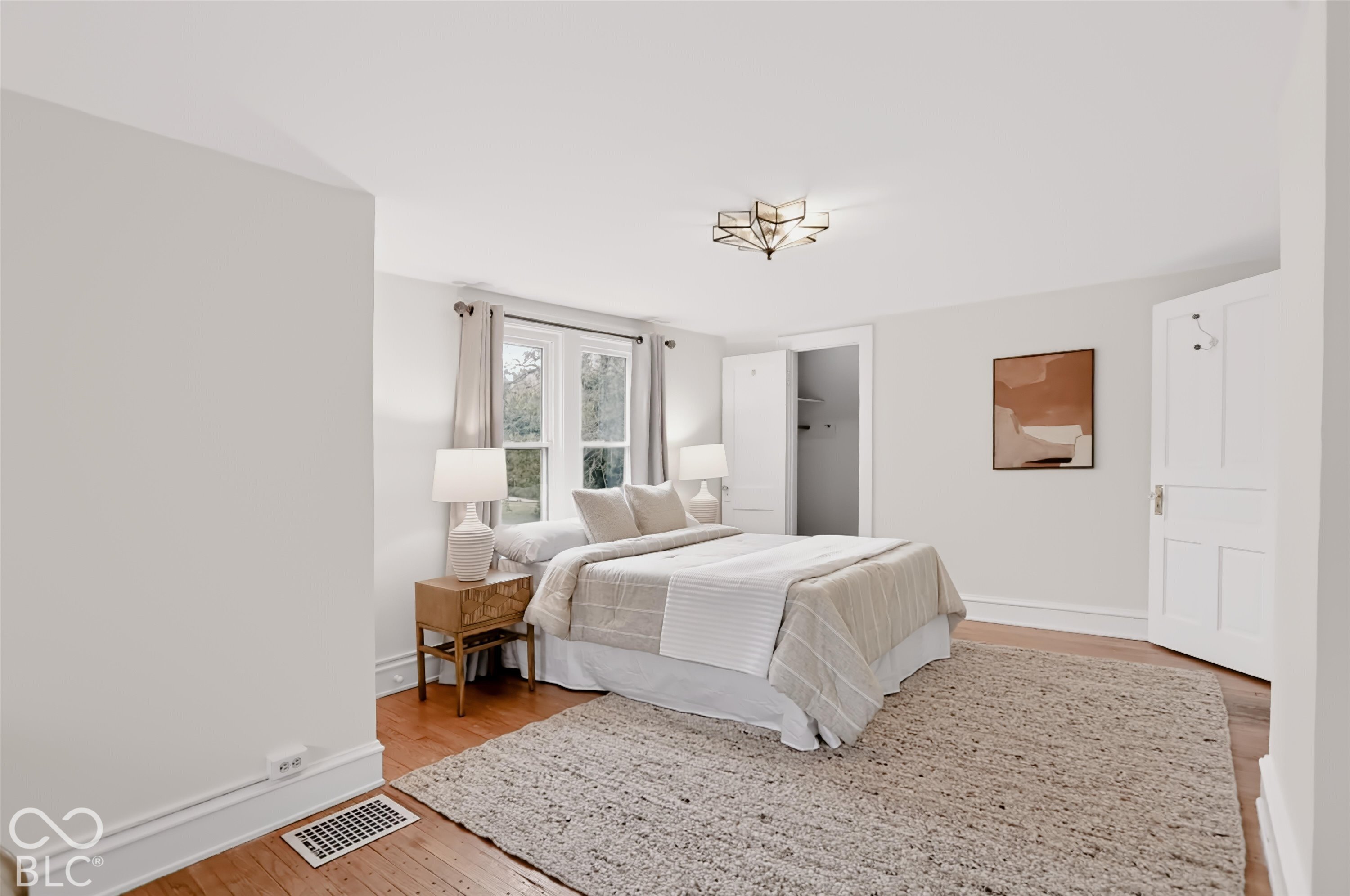 Neutral interior featuring wood-finish flooring, multi-pane windows, five-panel interior door, and geometric-style flush-mount lighting