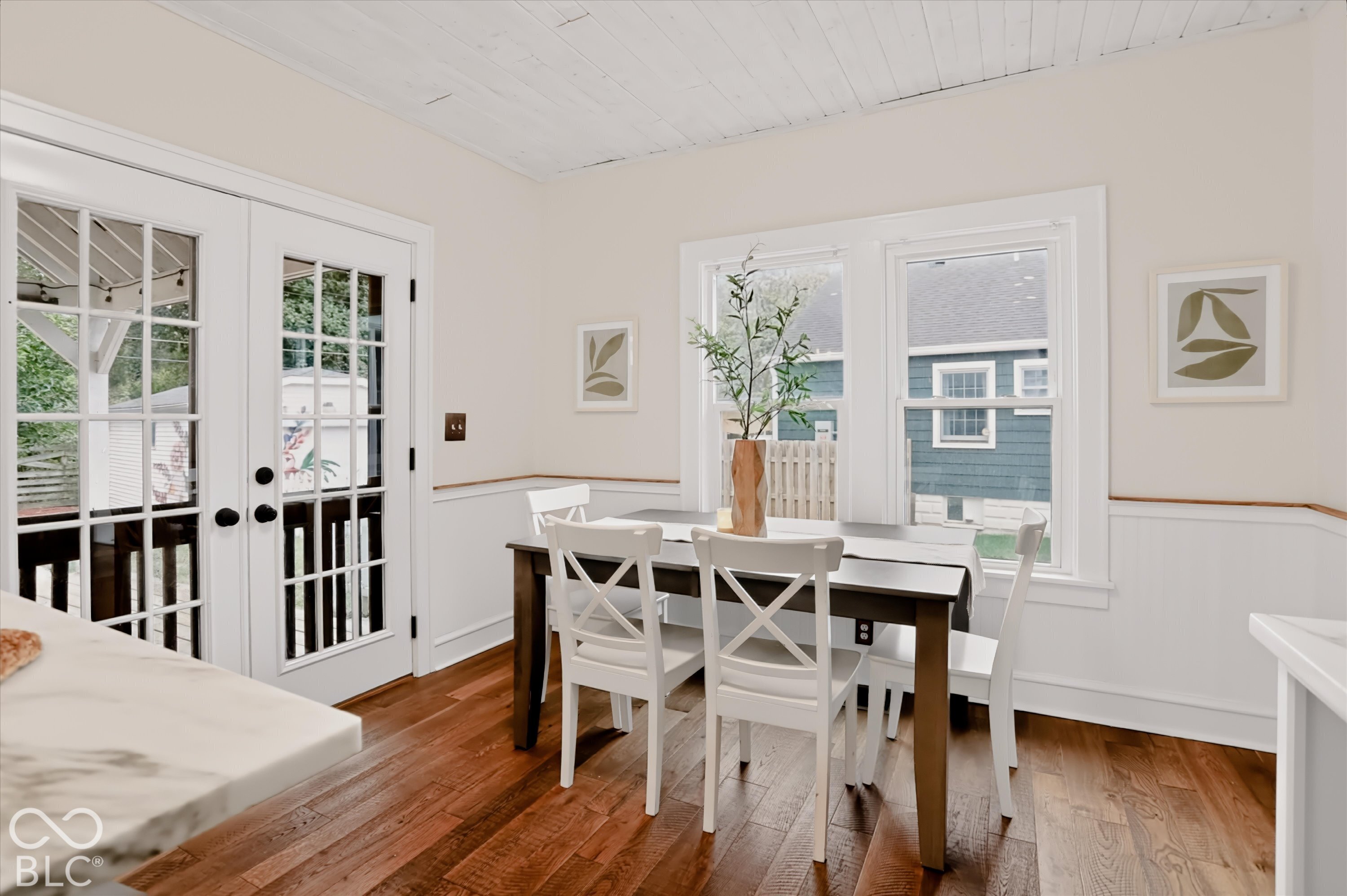 Wood-finish flooring, white beadboard wainscoting, glass-paned French doors, and a tongue-and-groove ceiling