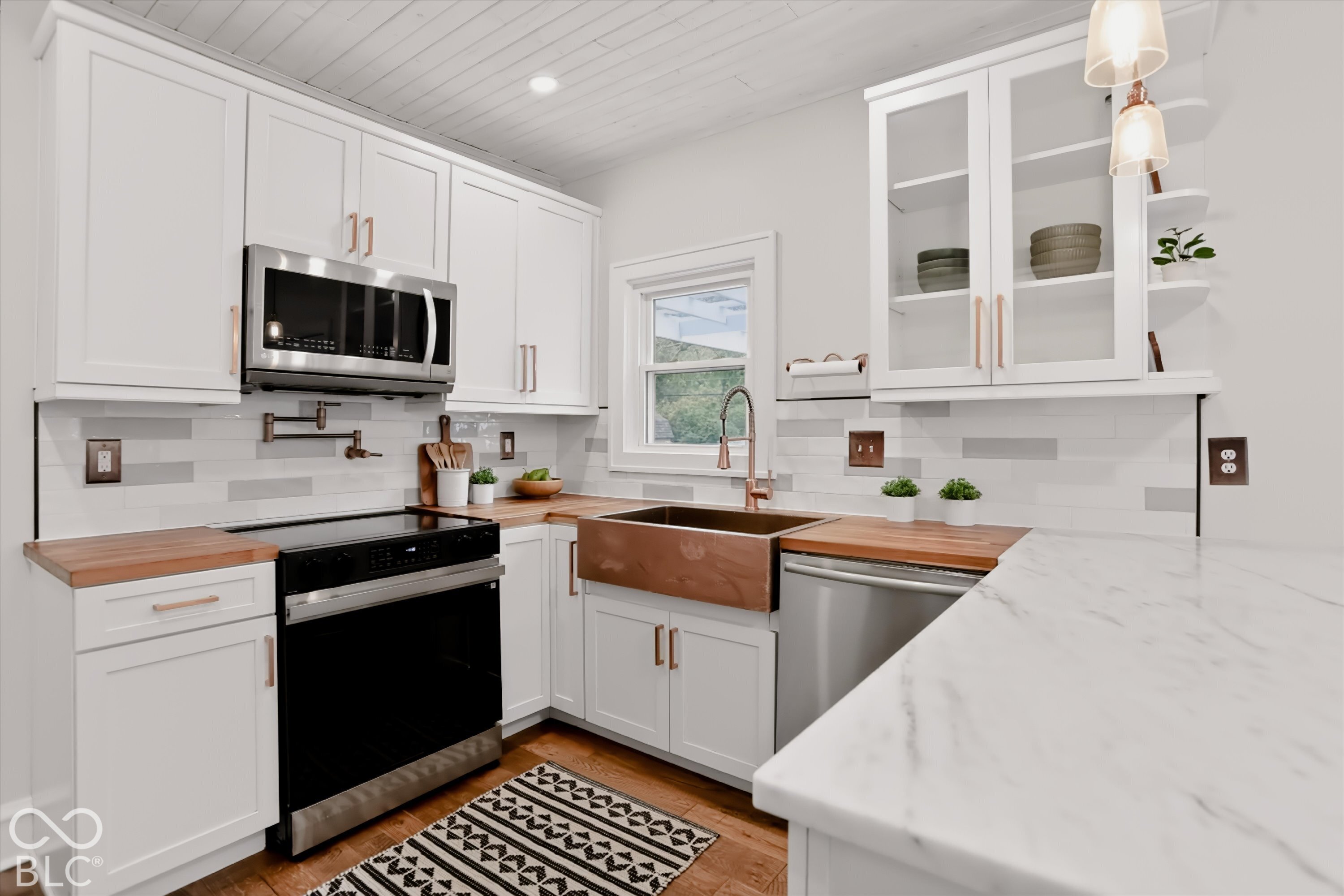 Kitchen featuring white shaker-style cabinetry, copper-finish hardware, a farmhouse-style copper sink, wood-finish countertops, and tongue-and-groove ceiling paneling