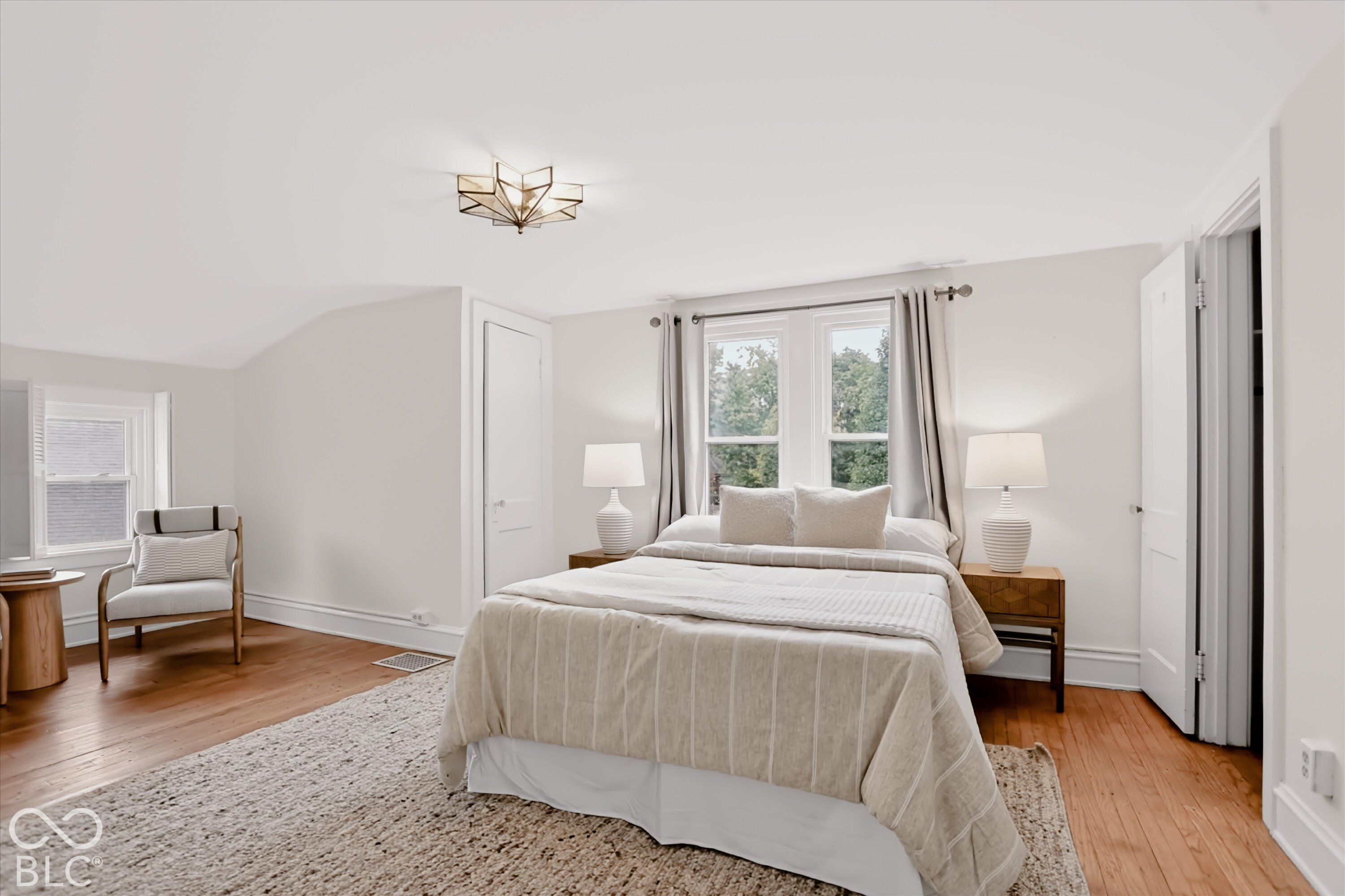 Bedroom featuring wood-finish flooring, multi-pane windows, and geometric ceiling-mounted lighting