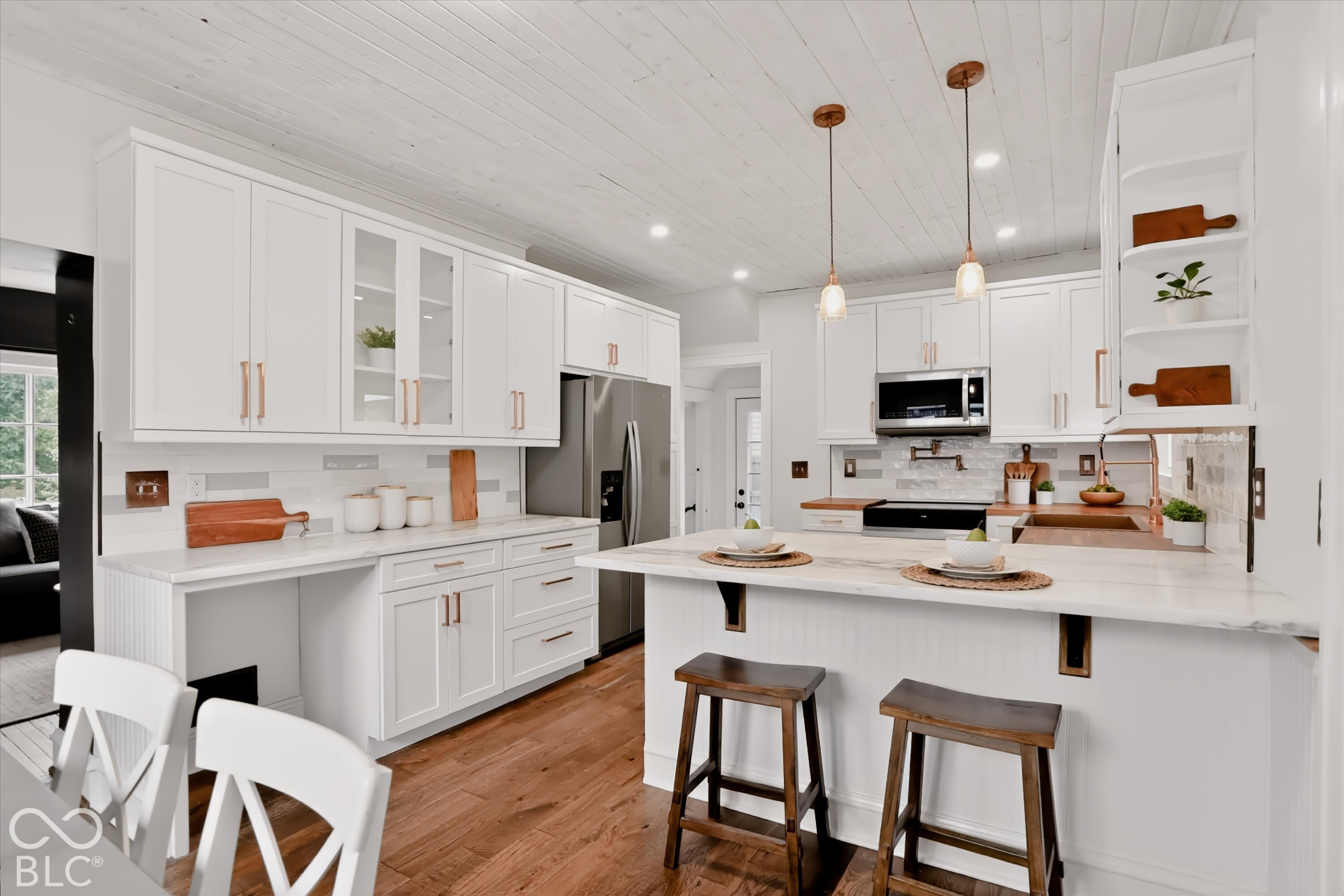 Kitchen featuring white cabinetry, wood-finish flooring, a stone-topped island, a beadboard ceiling, and metallic pendant lighting