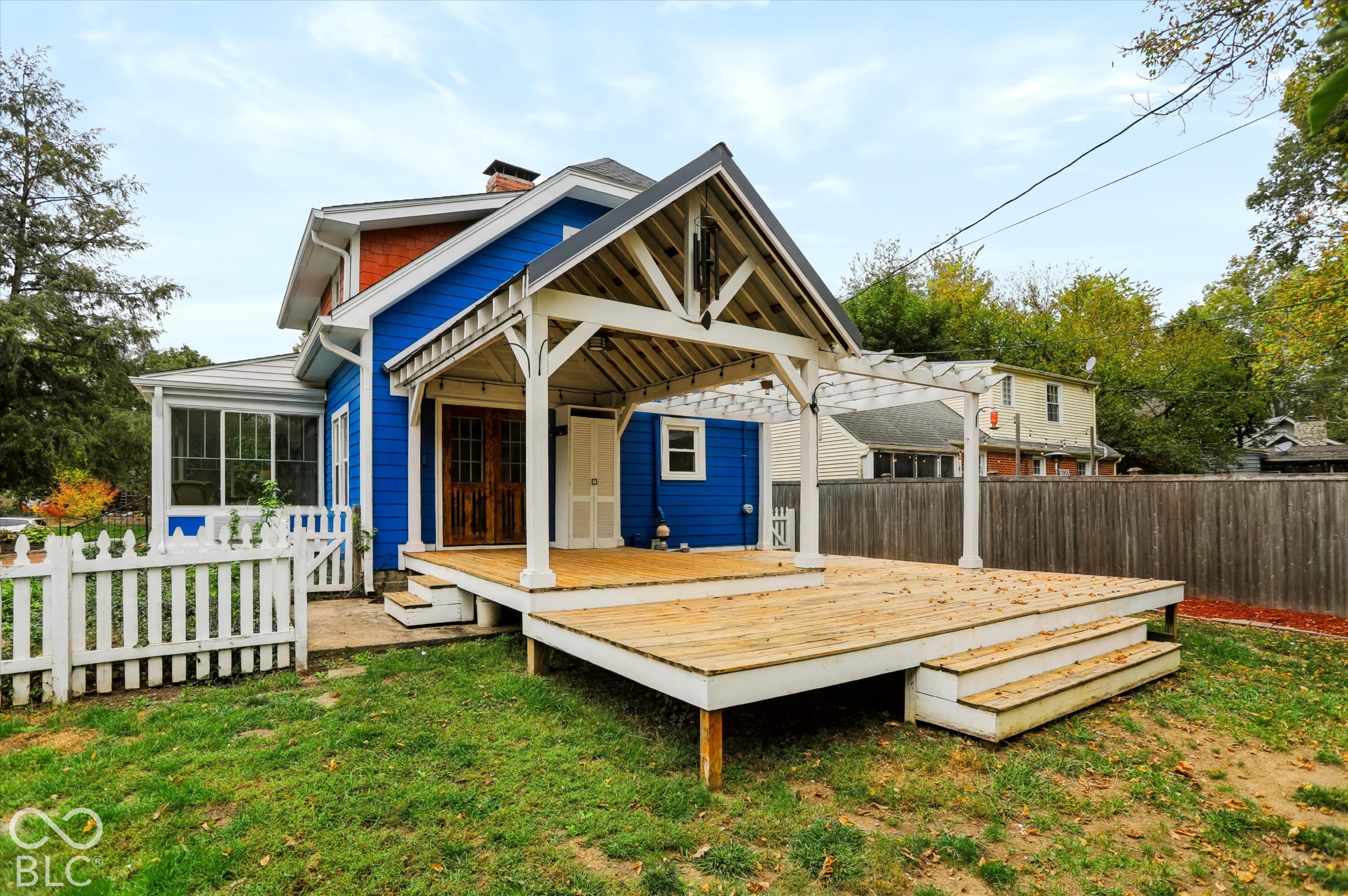 Exterior featuring a multi-level wood deck, covered gable porch with exposed timber framing, decorative pergola, and wood-finish French doors