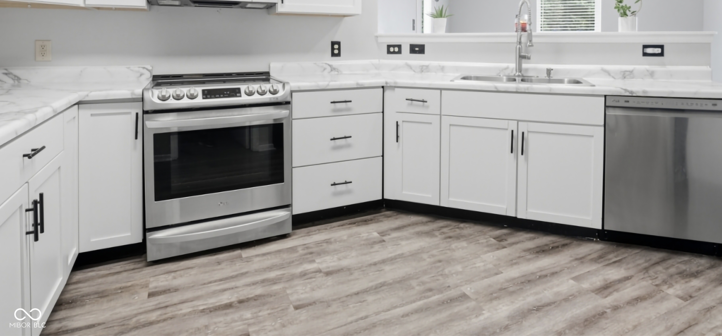 Modern kitchen featuring white cabinetry, stone-finish countertops, stainless steel appliances, and wood-finish flooring