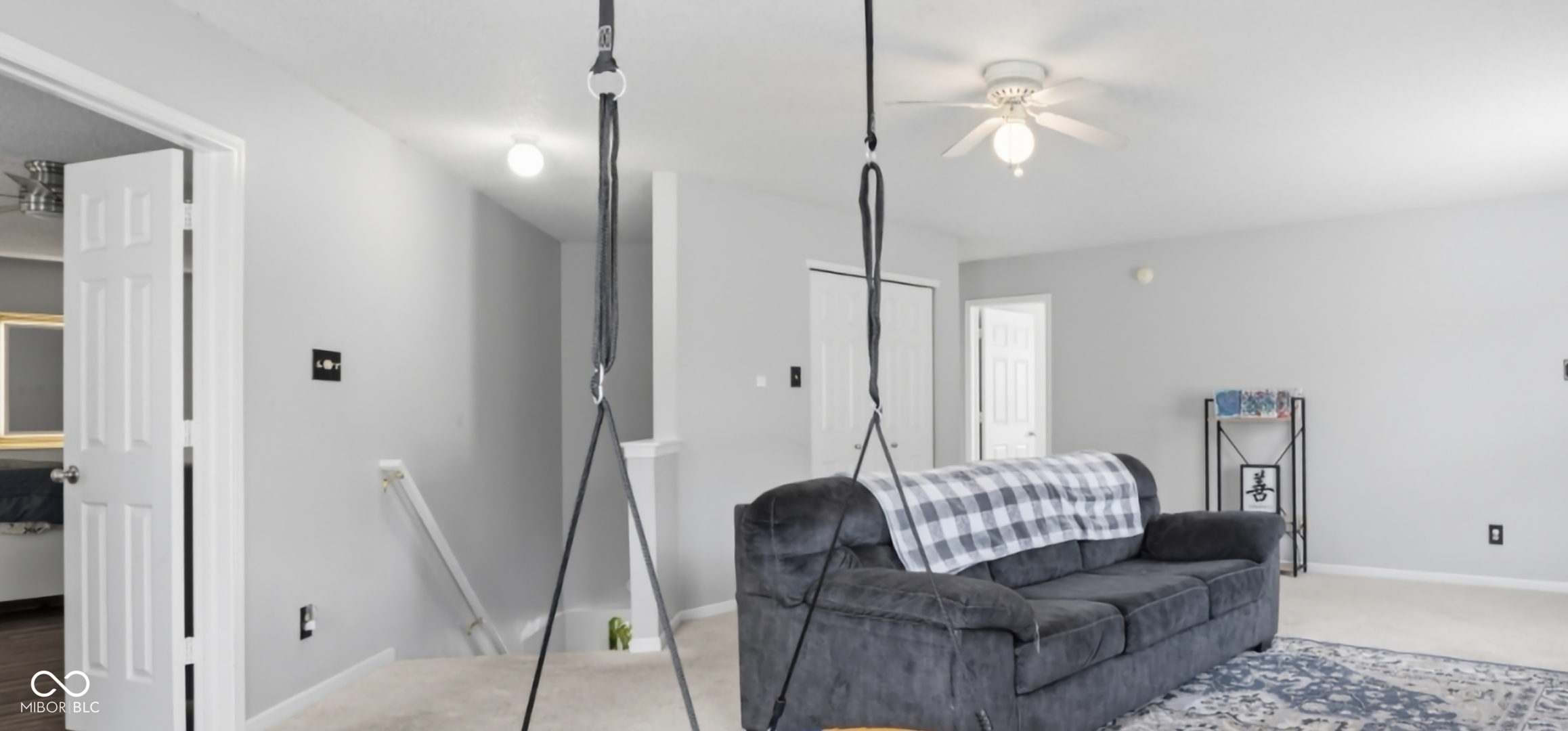 Open concept living space featuring light gray wall paint, a white ceiling fan with integrated lighting, and neutral carpeting