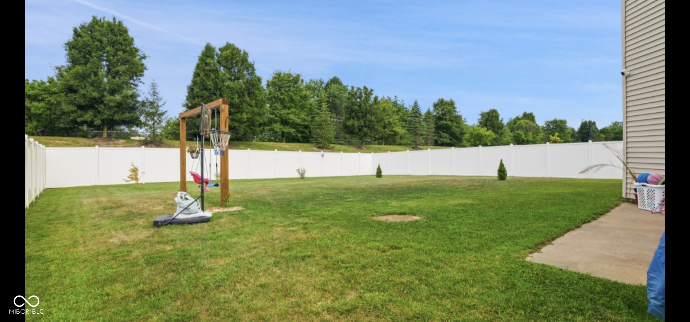 Expansive green lawn surrounded by a white privacy fence