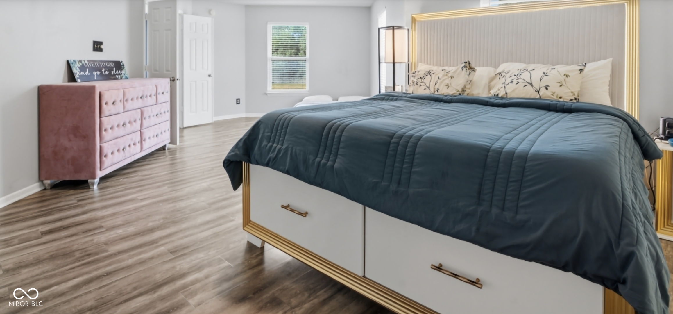Spacious room featuring wood-finish flooring, light grey walls, and a large window