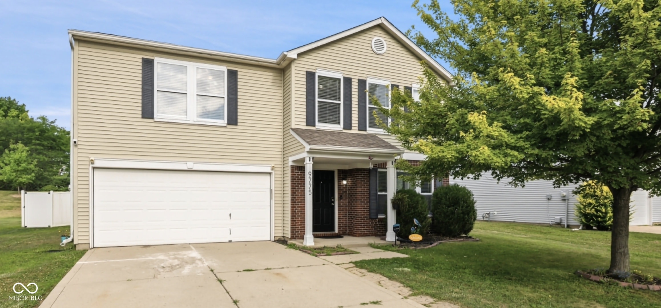 Two-story residence featuring light-toned horizontal siding with dark shutters, an attached garage, and a covered front entry