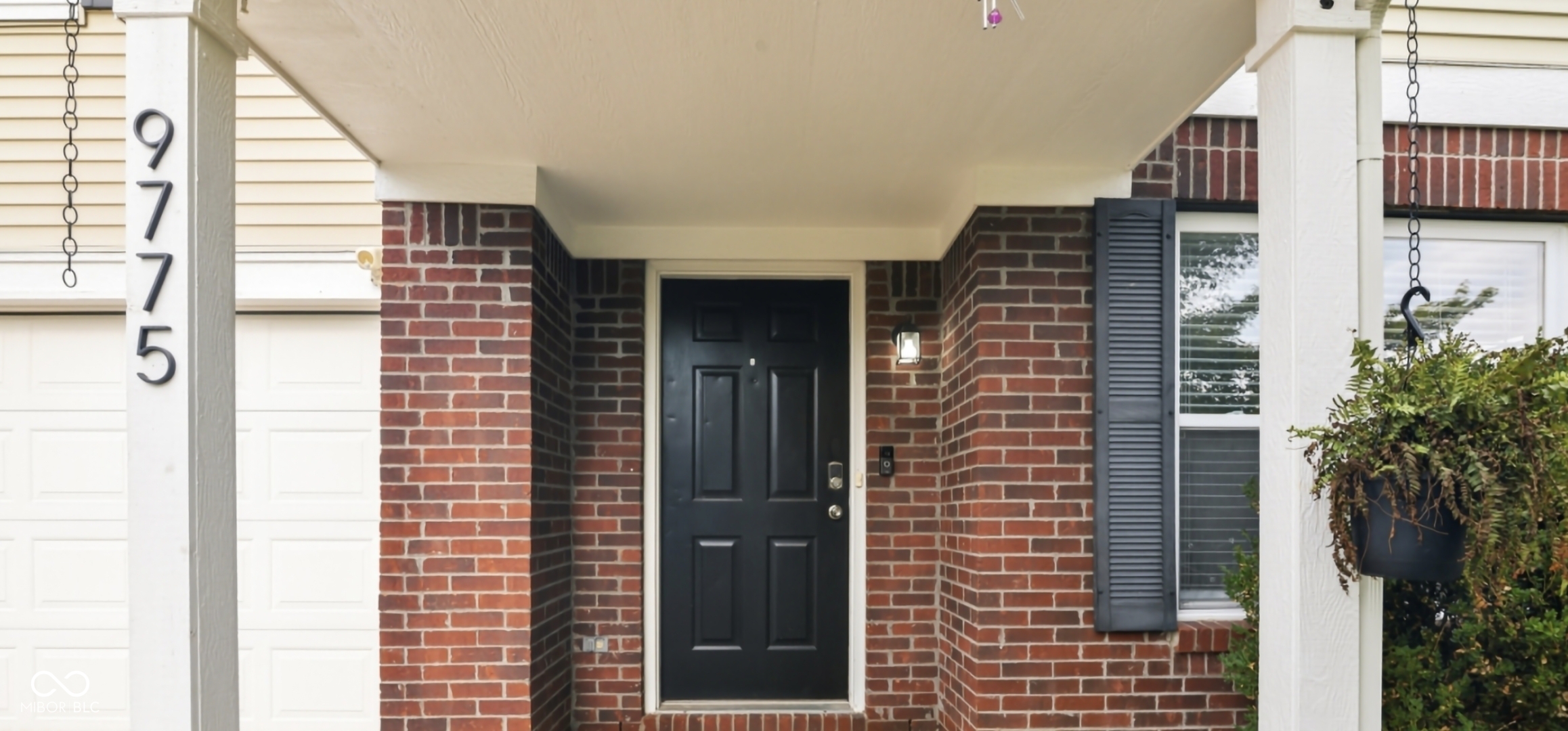 Brick facade with white trim accents and a black paneled entry door
