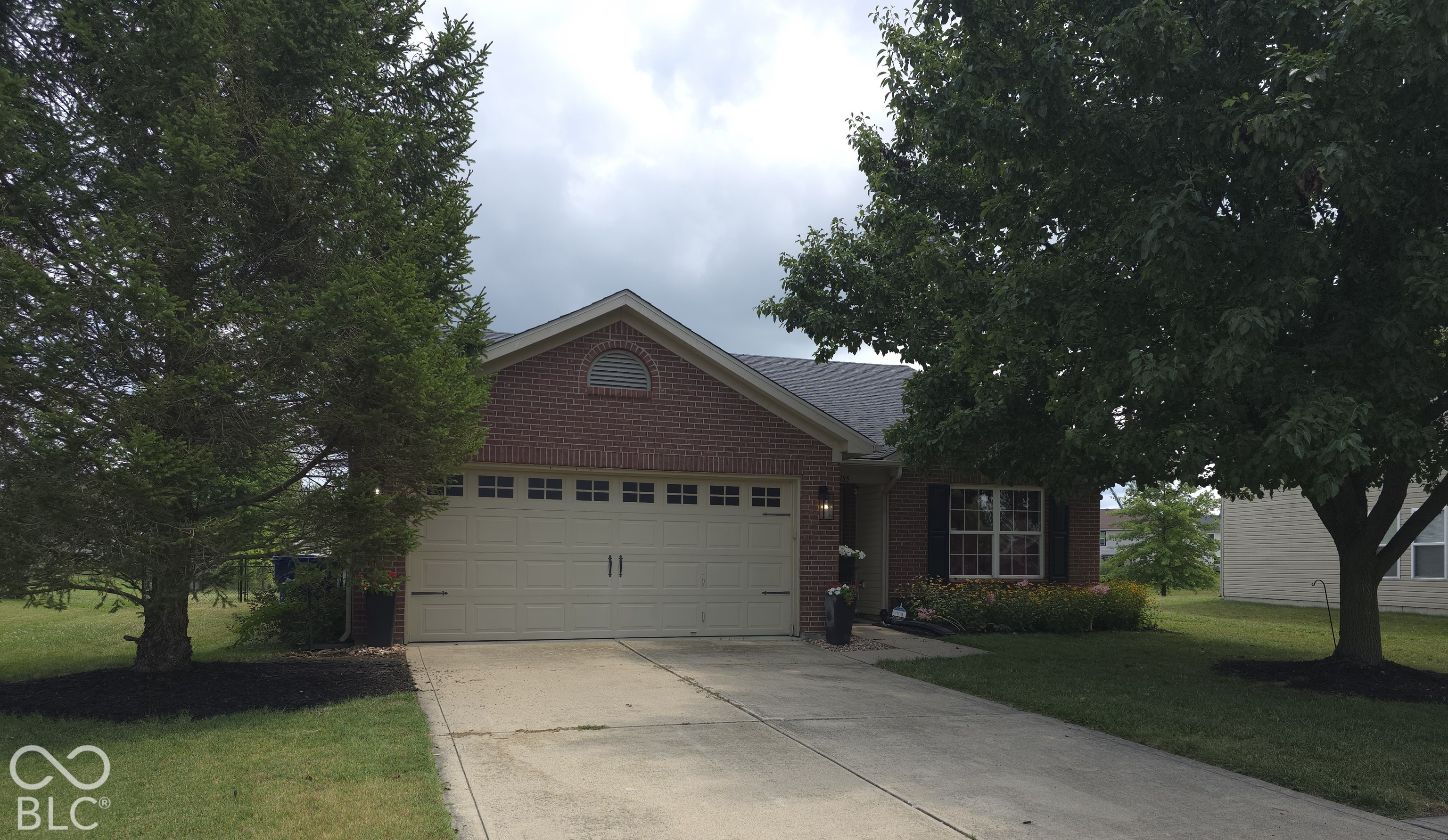 Brick exterior featuring a gabled roofline, an arched gable vent, and a multi-car garage with transom window detailing
