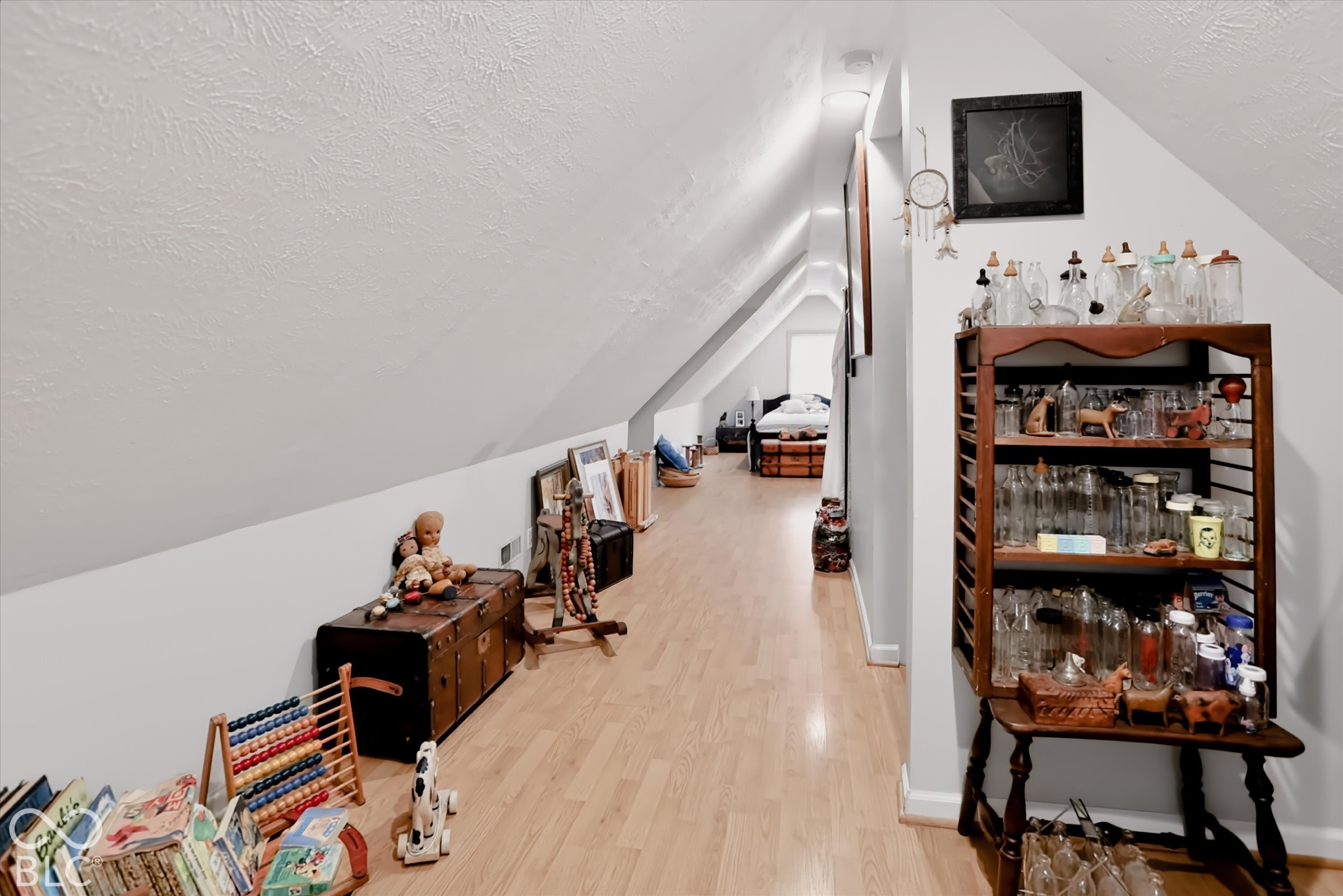 Finished attic space featuring vaulted ceilings, neutral wall paint, and wood-finish flooring