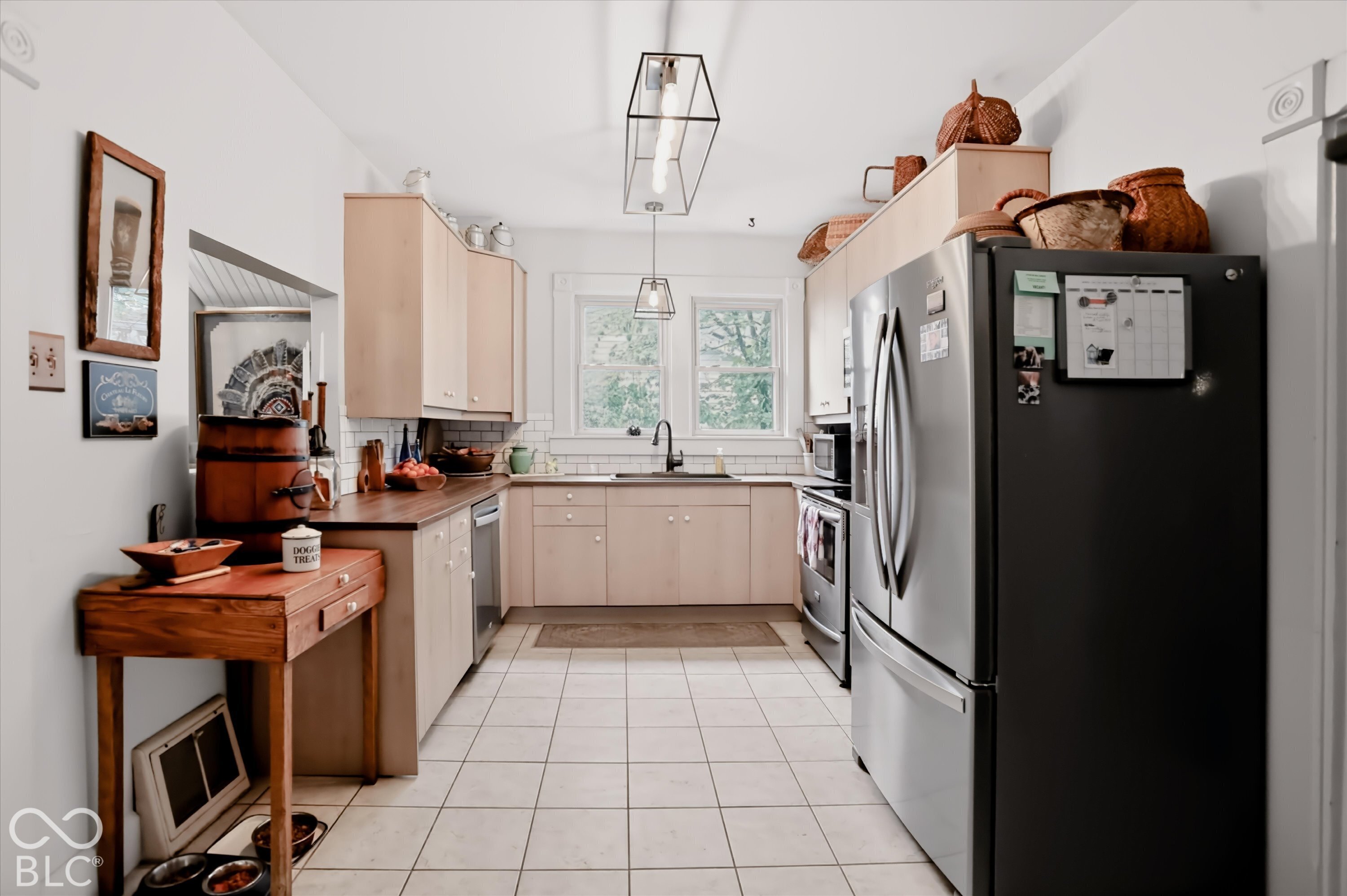 Kitchen featuring light-finish cabinetry, dark solid-surface countertops, subway tile backsplash, stainless steel appliances, and rectangular tile flooring