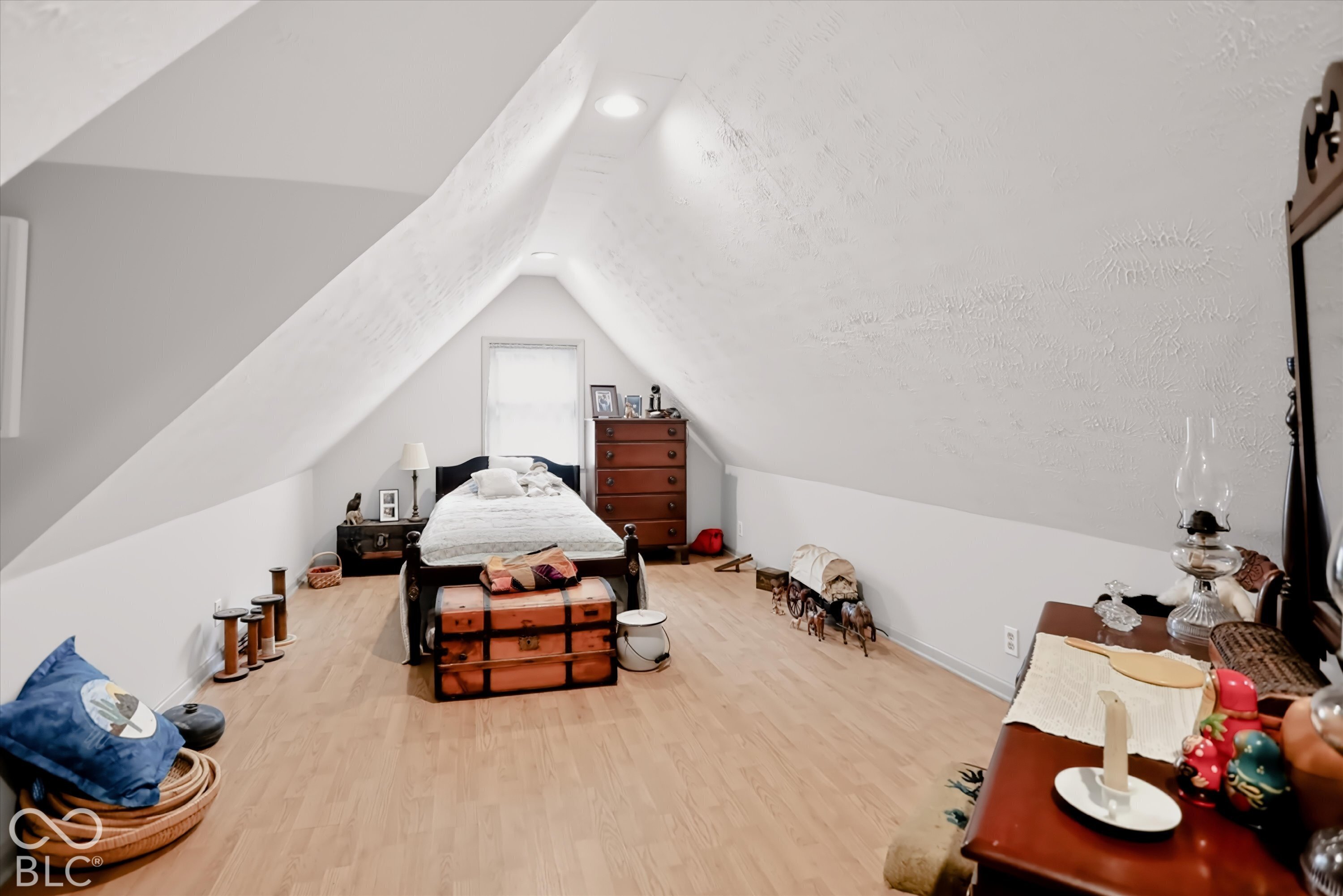 Vaulted ceiling with angled walls, recessed lighting, and wood-finish flooring