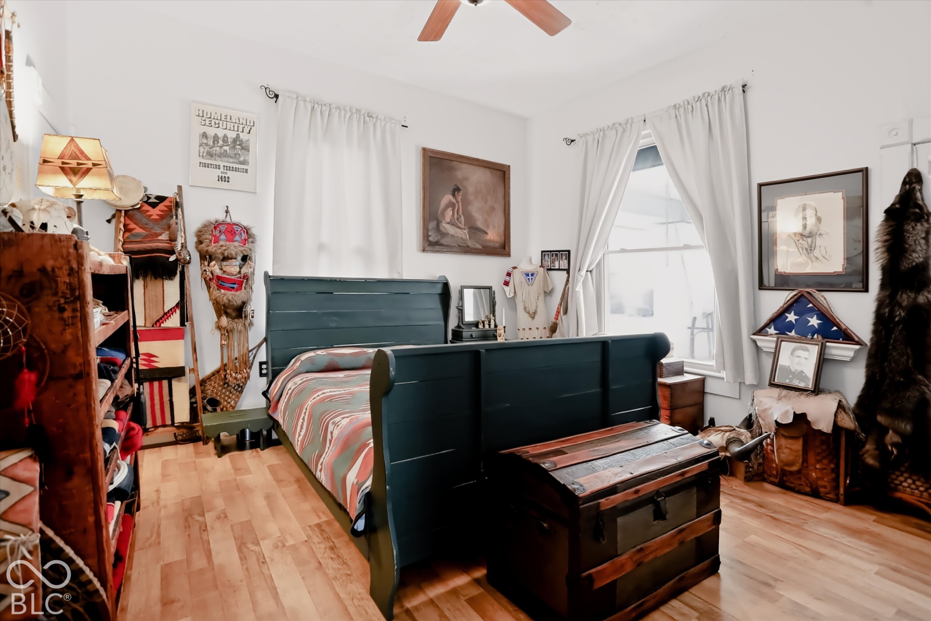 Room featuring wood-finish flooring, dual windows with curtains, and a ceiling fan