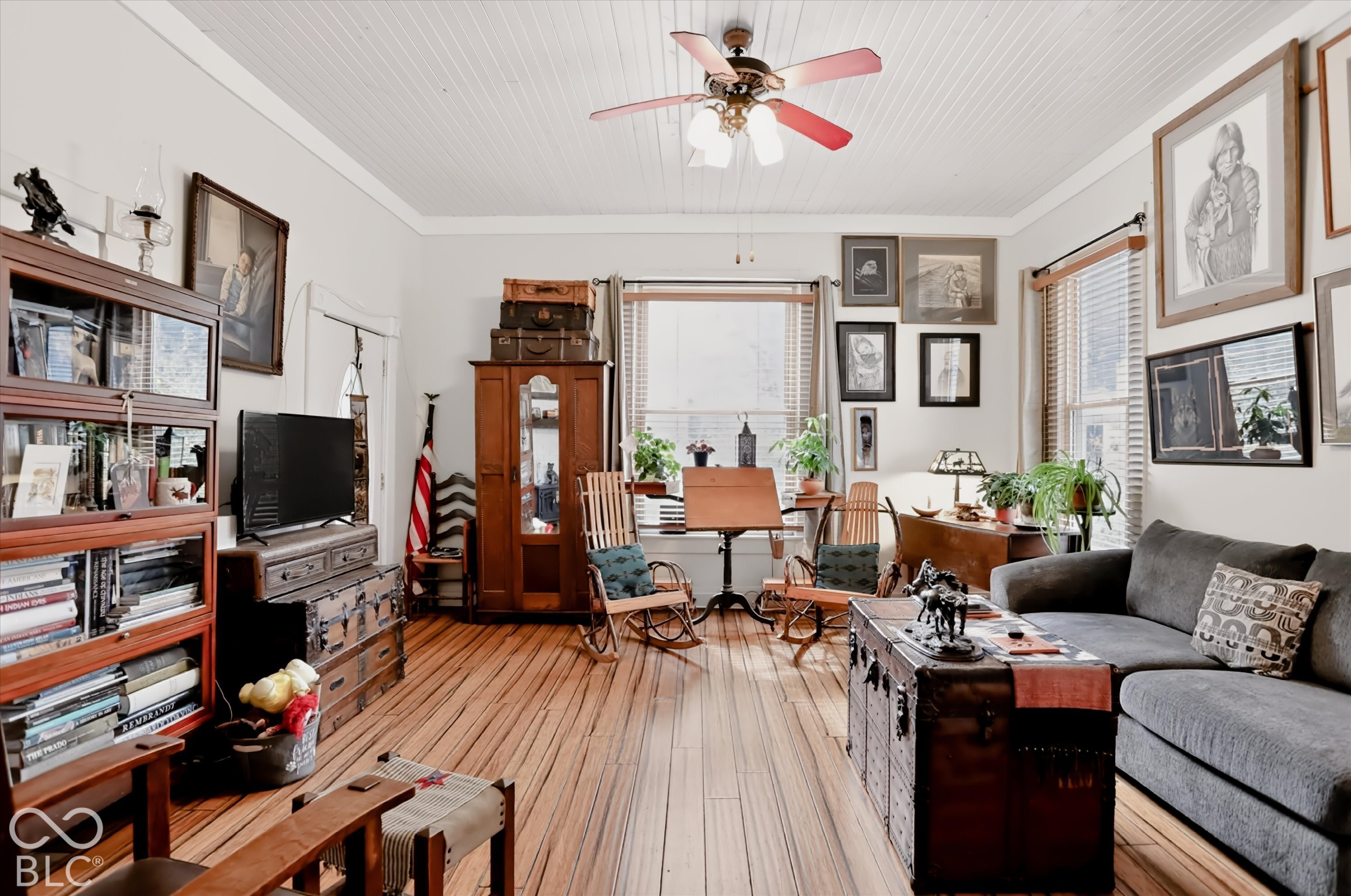 Living space featuring vertical beadboard ceiling, wood-finish flooring, and a ceiling-mounted light fixture with a fan