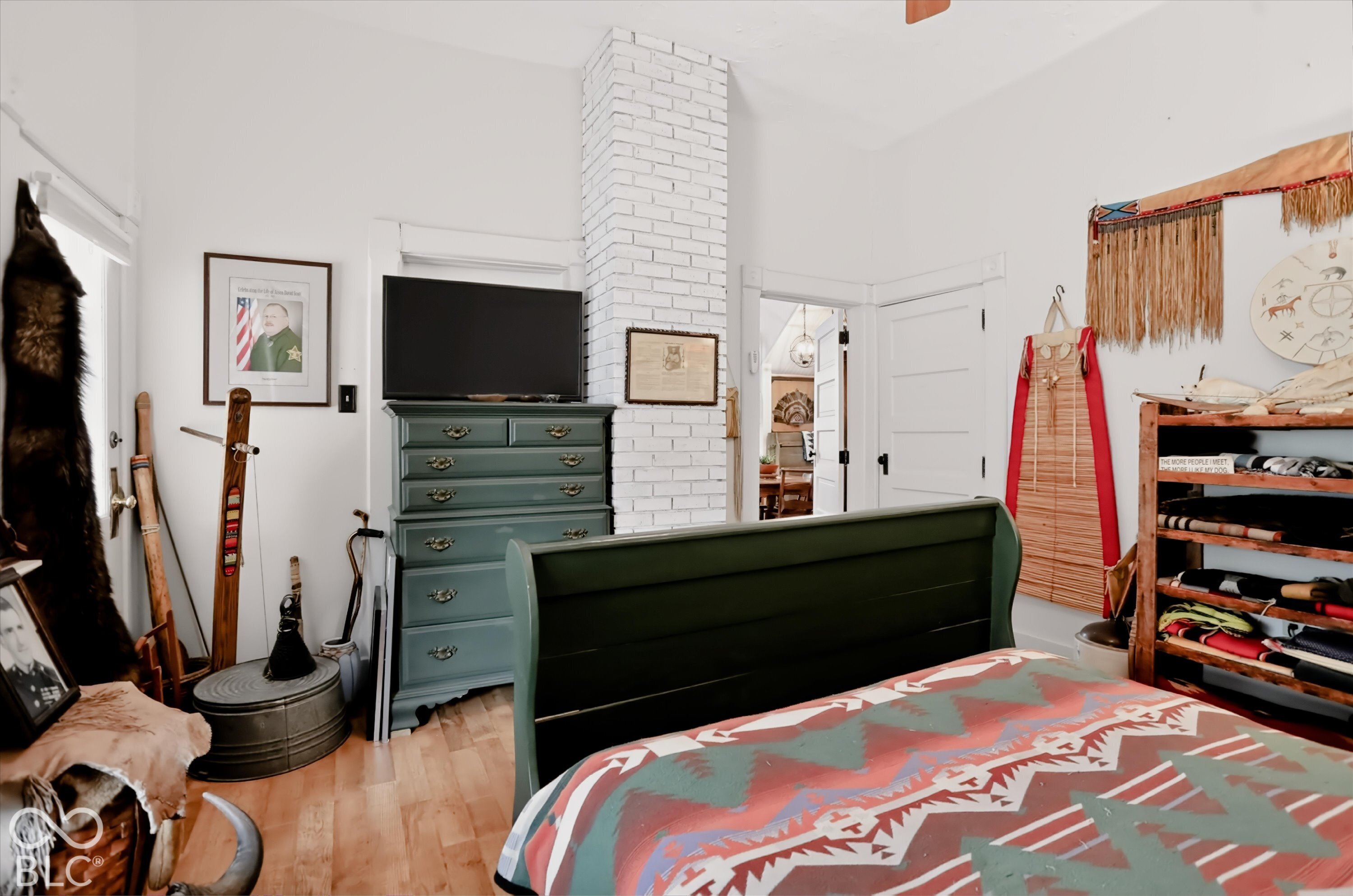 Exposed white-painted brick chimney, wood-finish flooring, and solid-core interior doors with traditional millwork trim