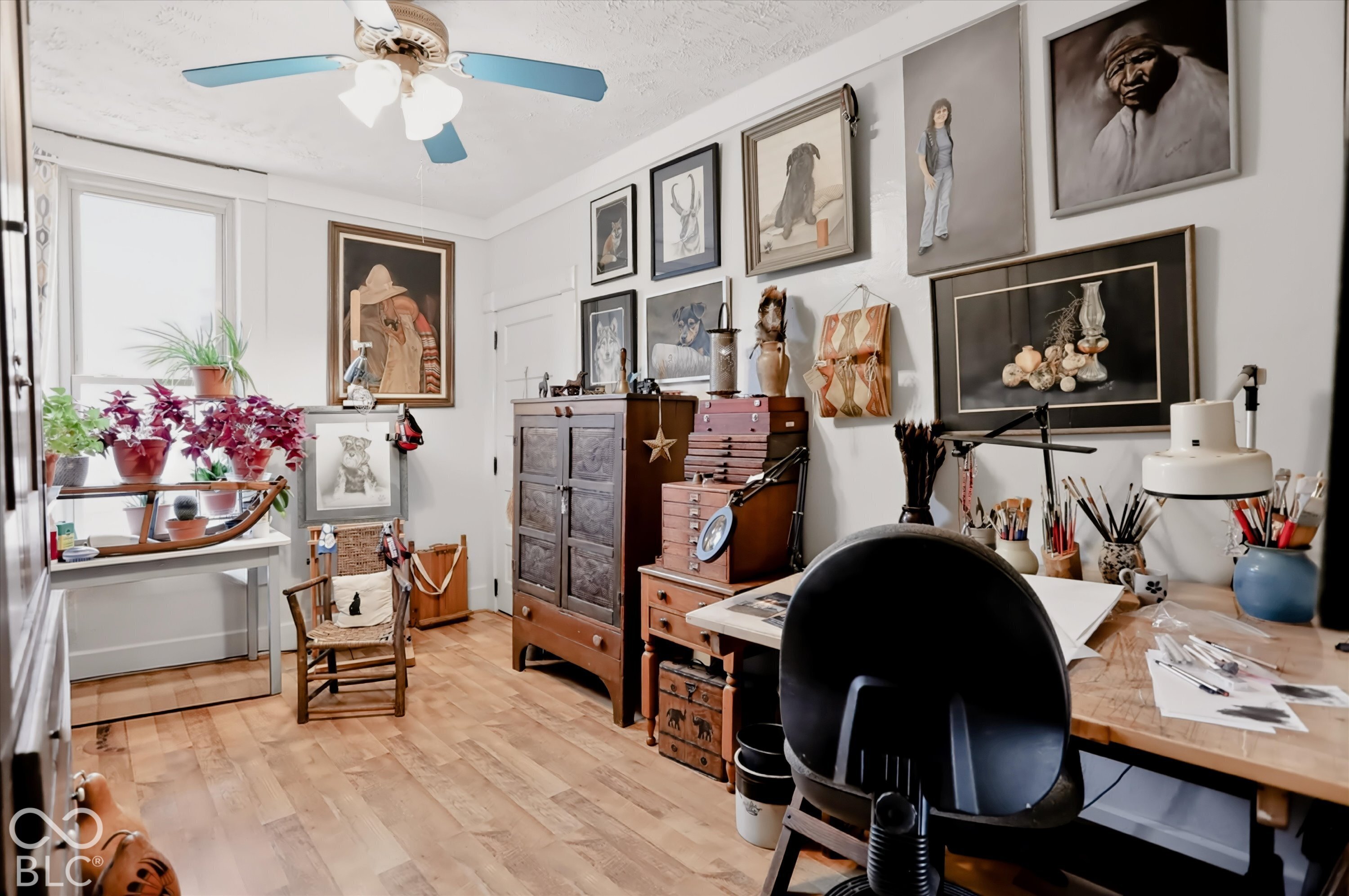 Interior room featuring wood-finish flooring, white walls, a dual-pane window, and a ceiling-mounted light fixture with a fan