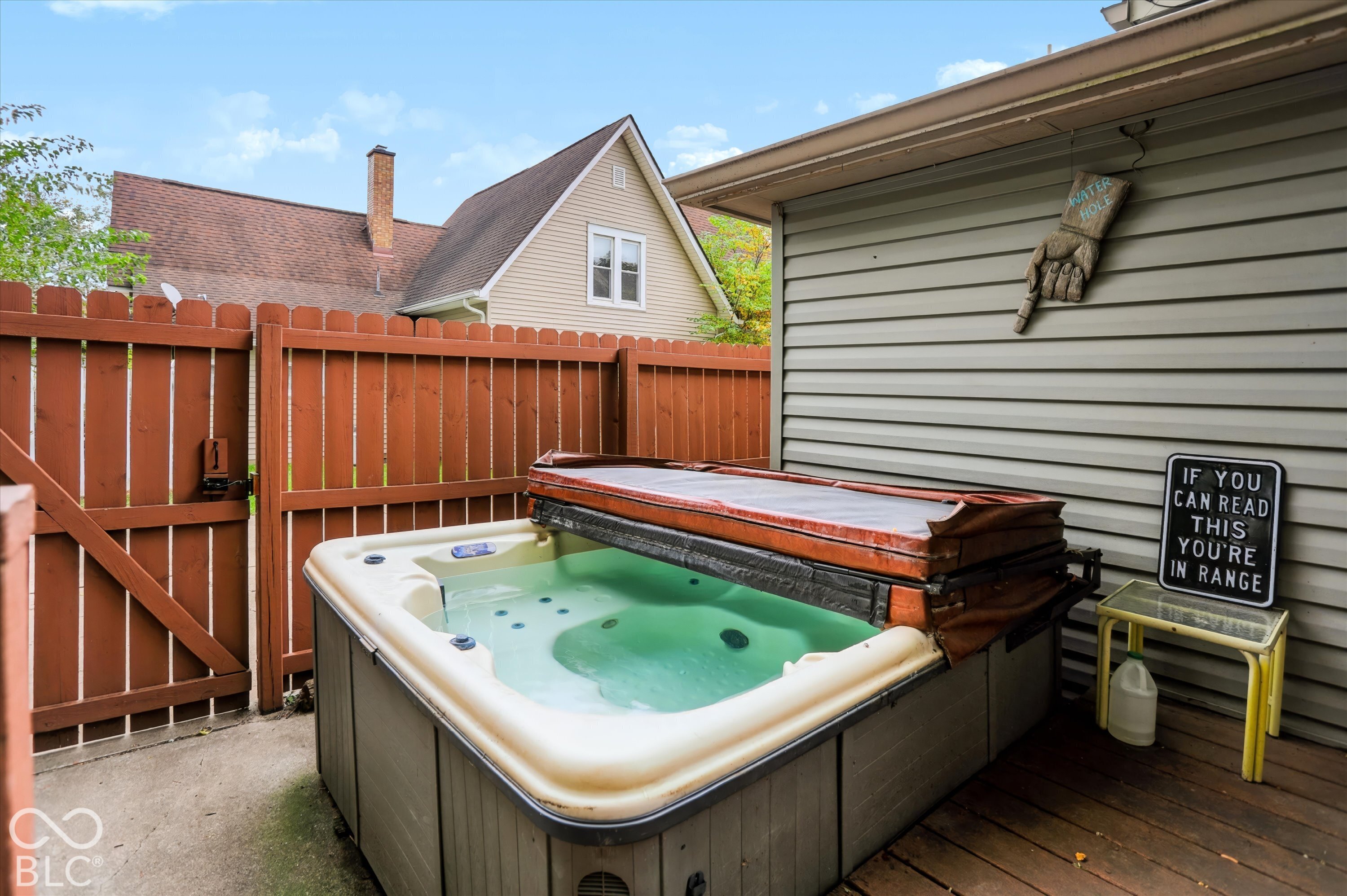 Outdoor hot tub featuring a hard cover, wood-slat privacy fencing, and a concrete patio surface
